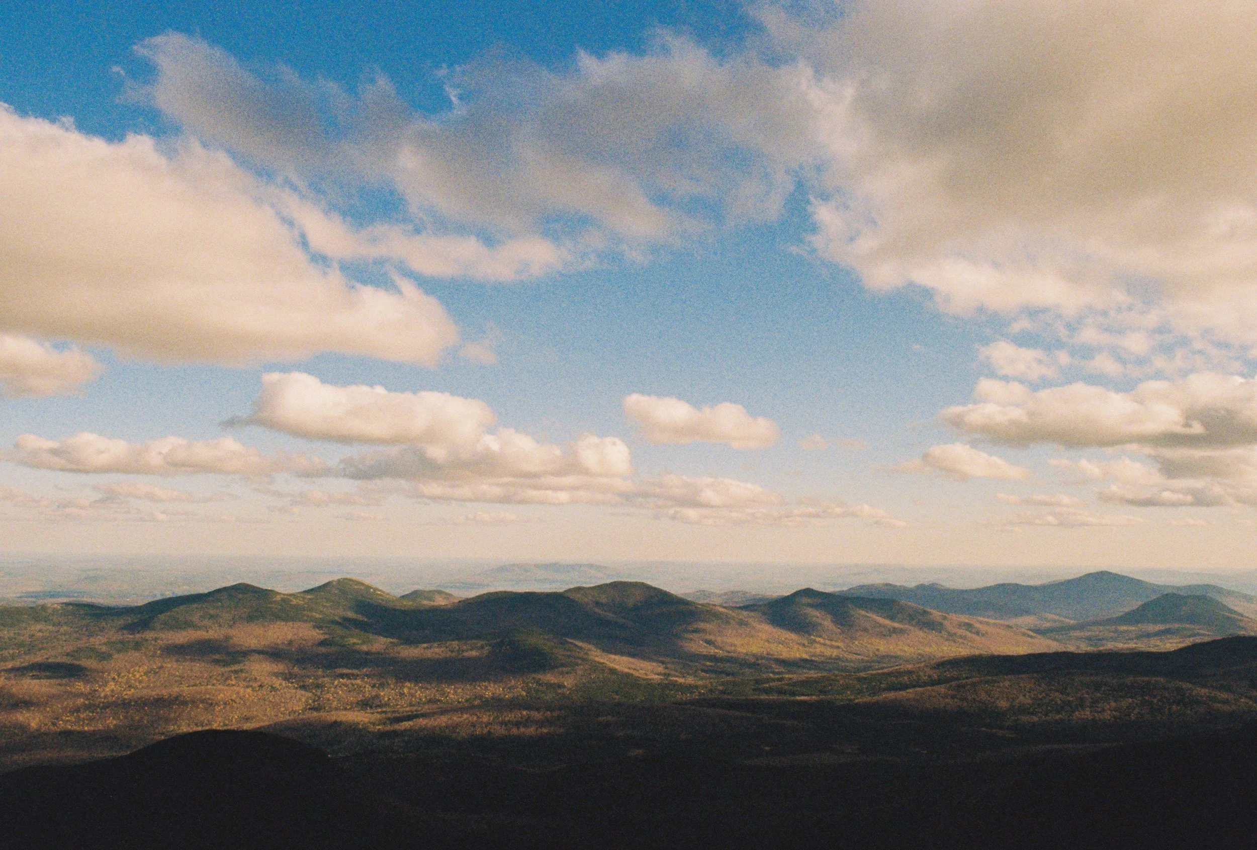 Scenic view of rolling green hills under a partly cloudy sky during daytime.