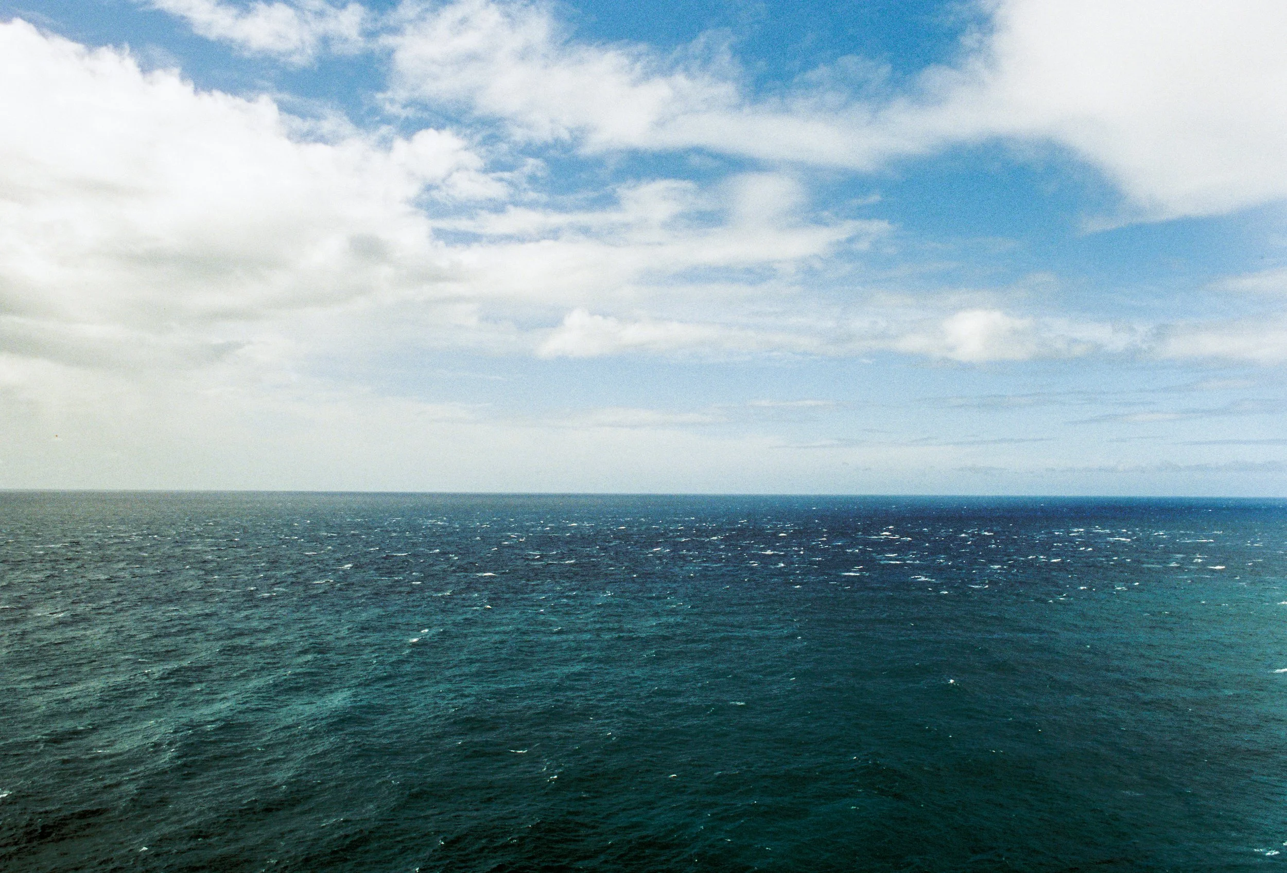 Open ocean with blue water and a partly cloudy sky.