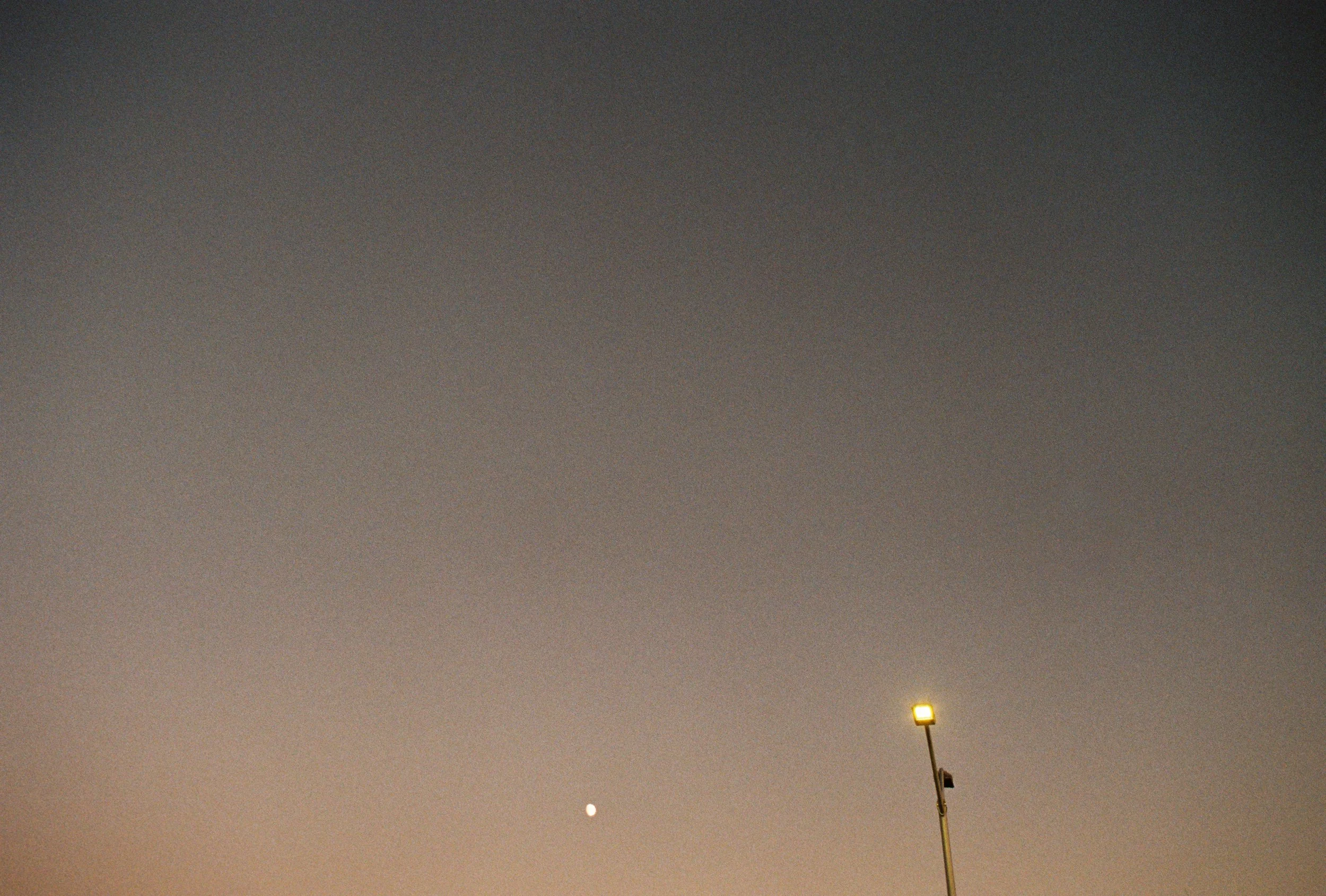 Night sky with visible moon and streetlight on a tall pole