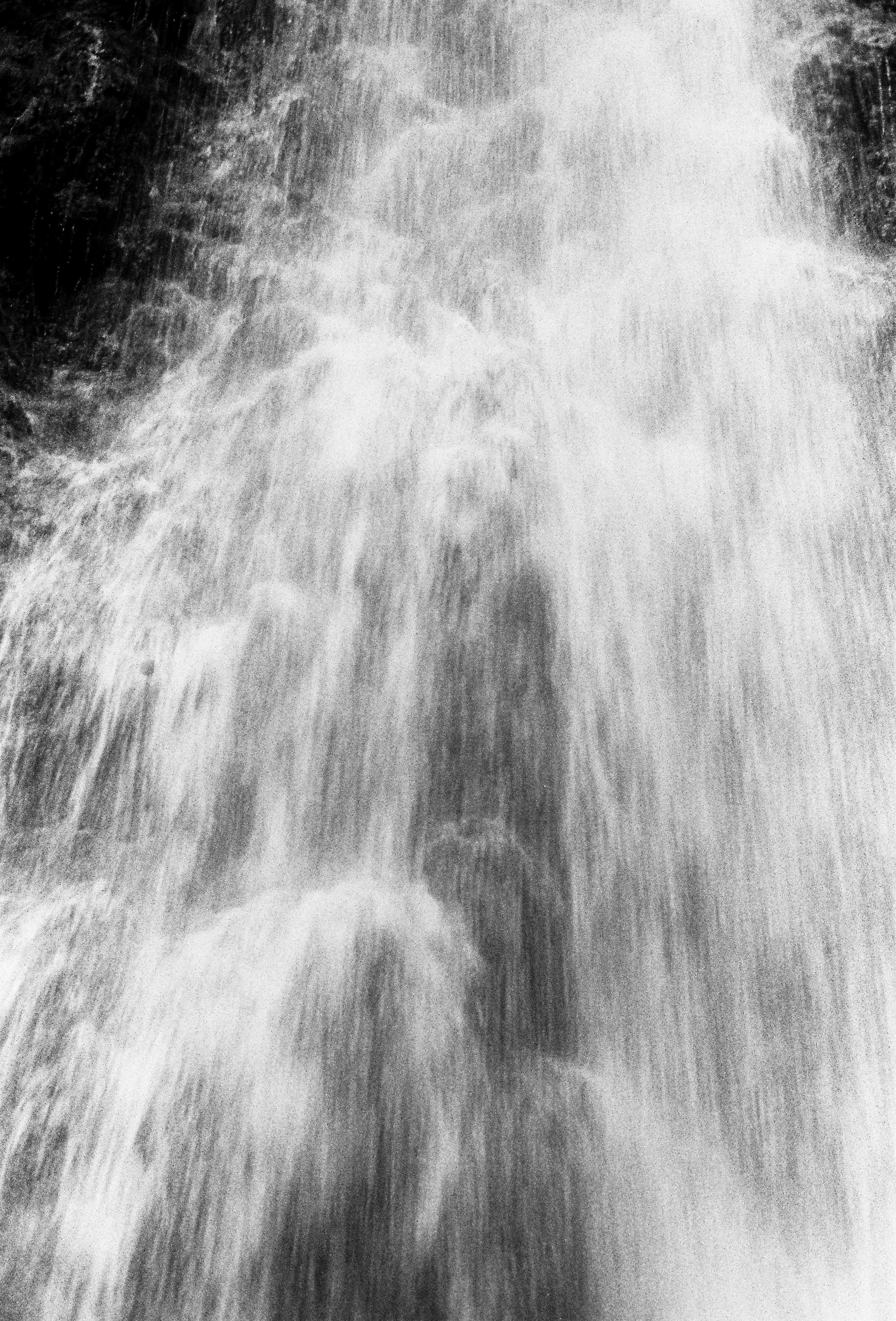Shadow of a person walking through a water spray or waterfall, creating a silhouette.