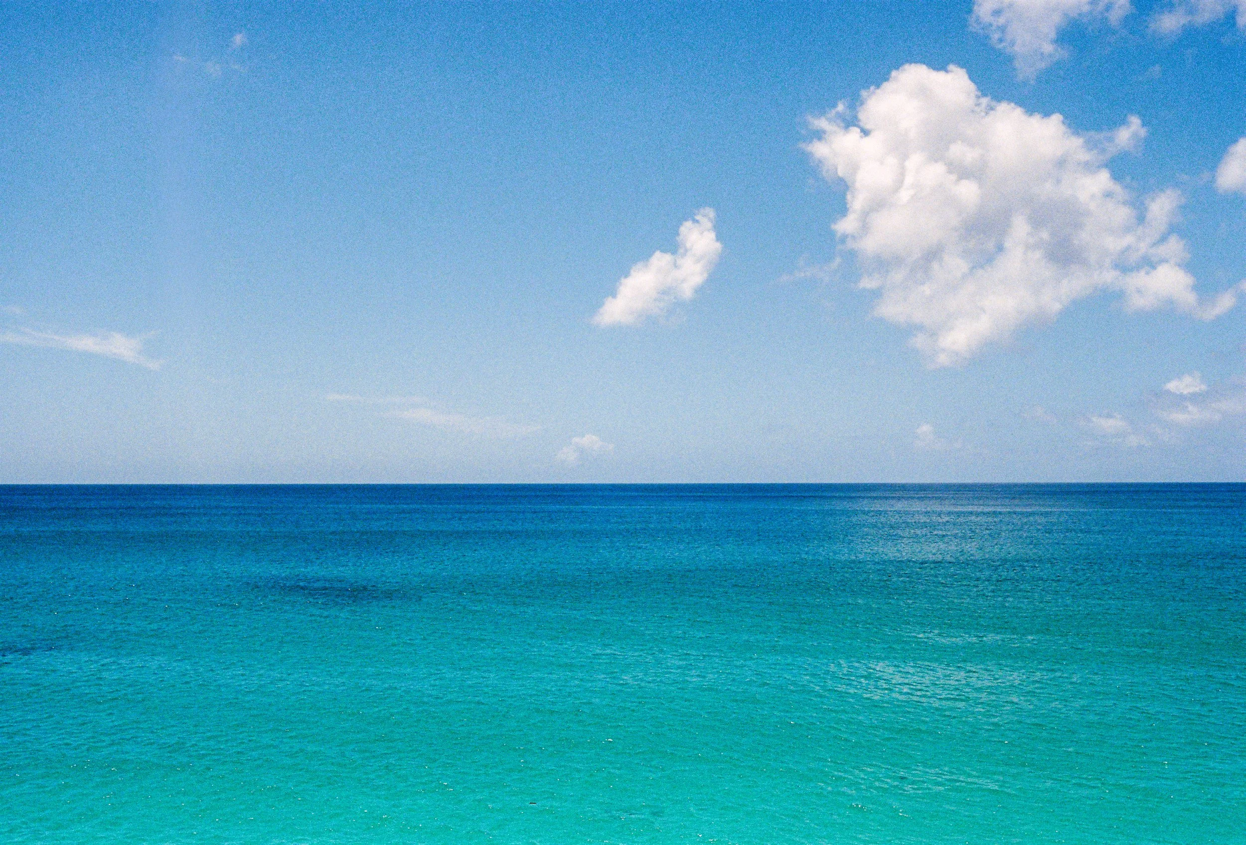 Ocean with clear, blue water and a partly cloudy sky.