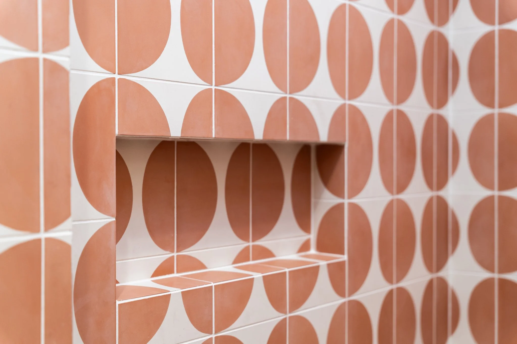 Patterned tile carries through the shower niche, making storage part of the design. Project by Rhino Building Group.