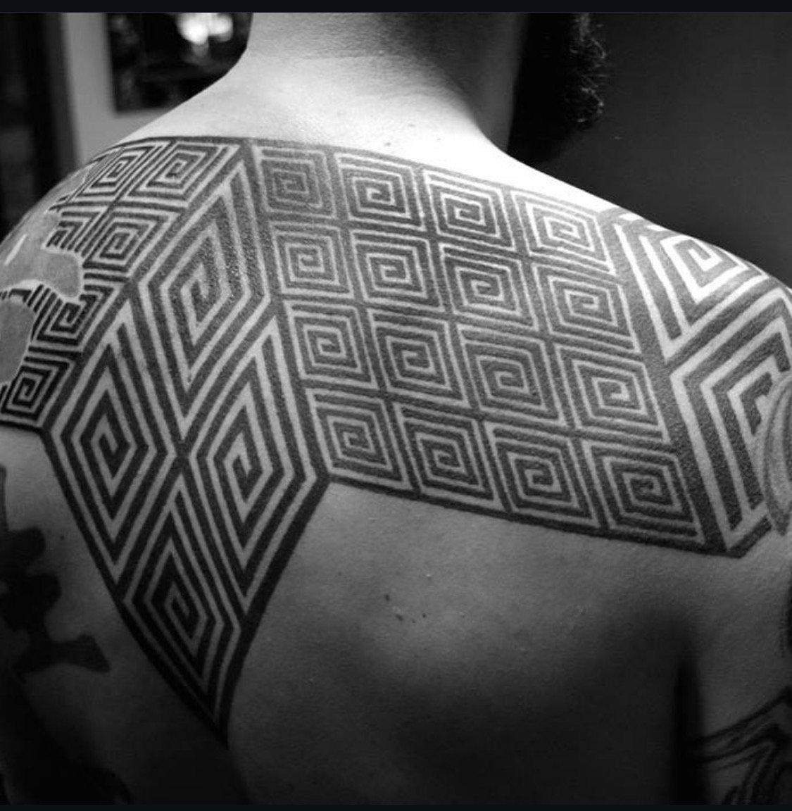 Geometric black ornamental tattoo across the shoulders and upper back