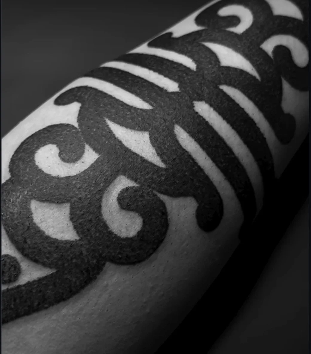 Close view of a curved black ornamental tattoo.