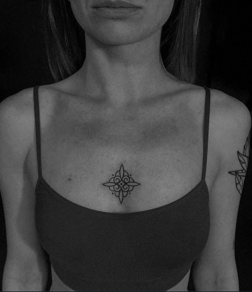 Small symmetrical ornamental tattoo at the centre of the chest.