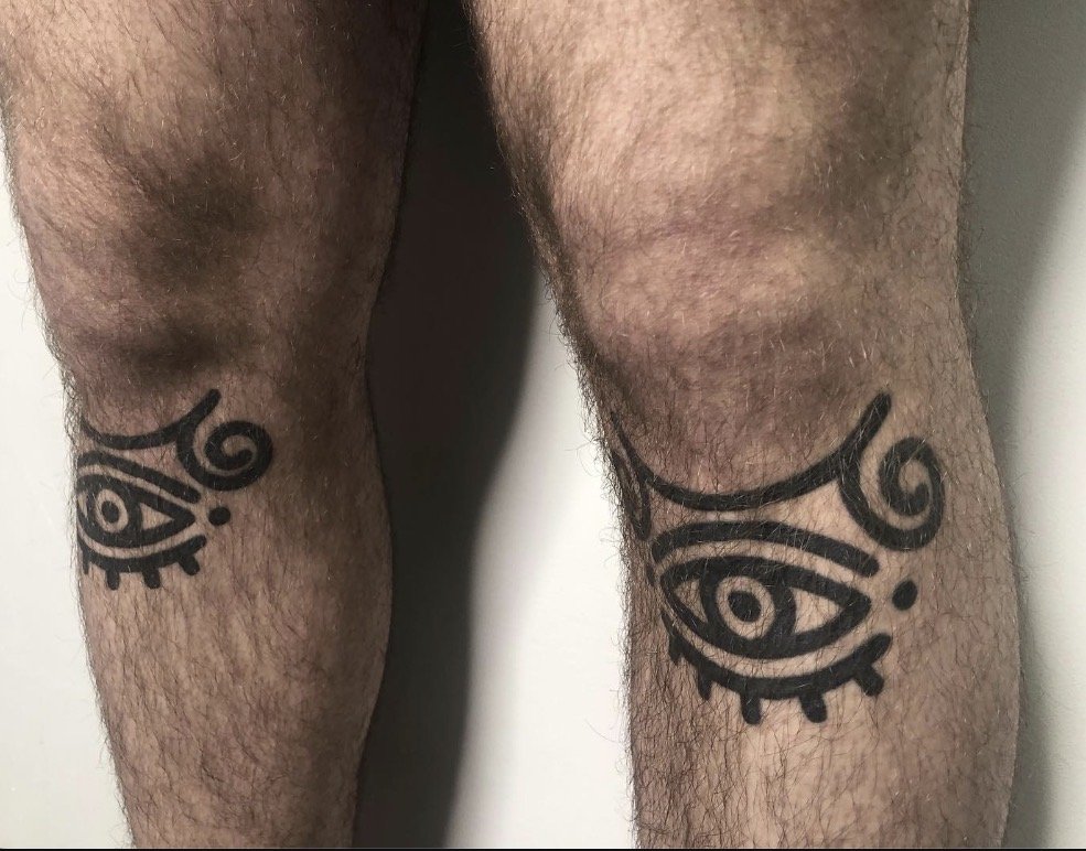 Symmetrical eye tattoos on both knees.