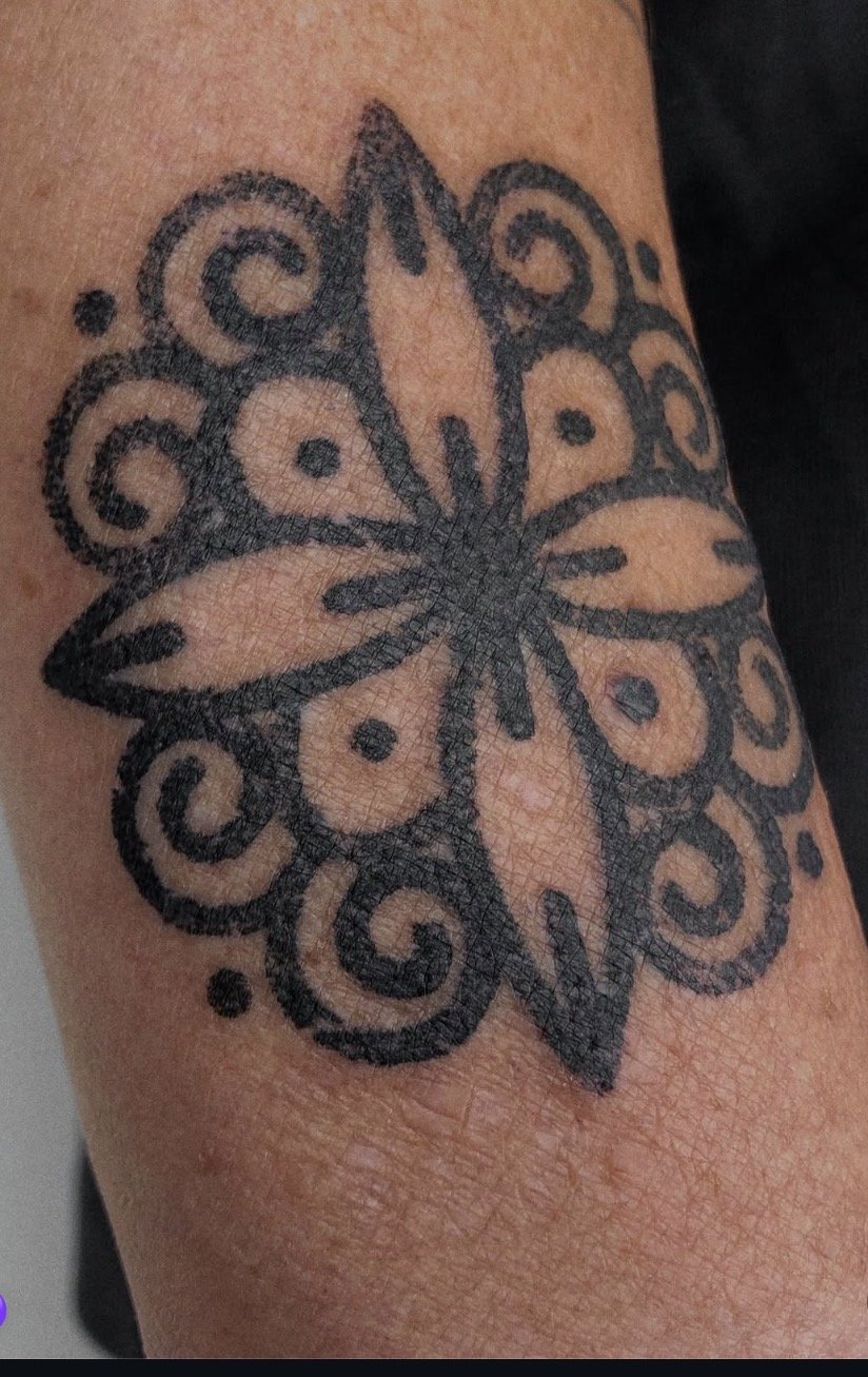 Black floral ornamental tattoo in close detail.