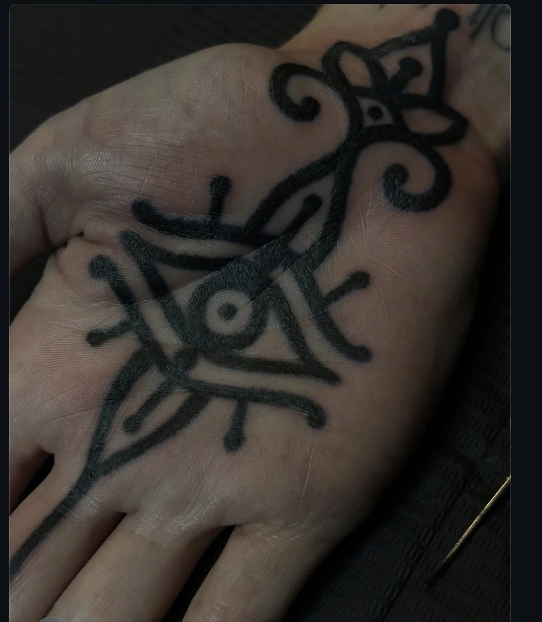 Ornamental tattoo across the back of the hand.