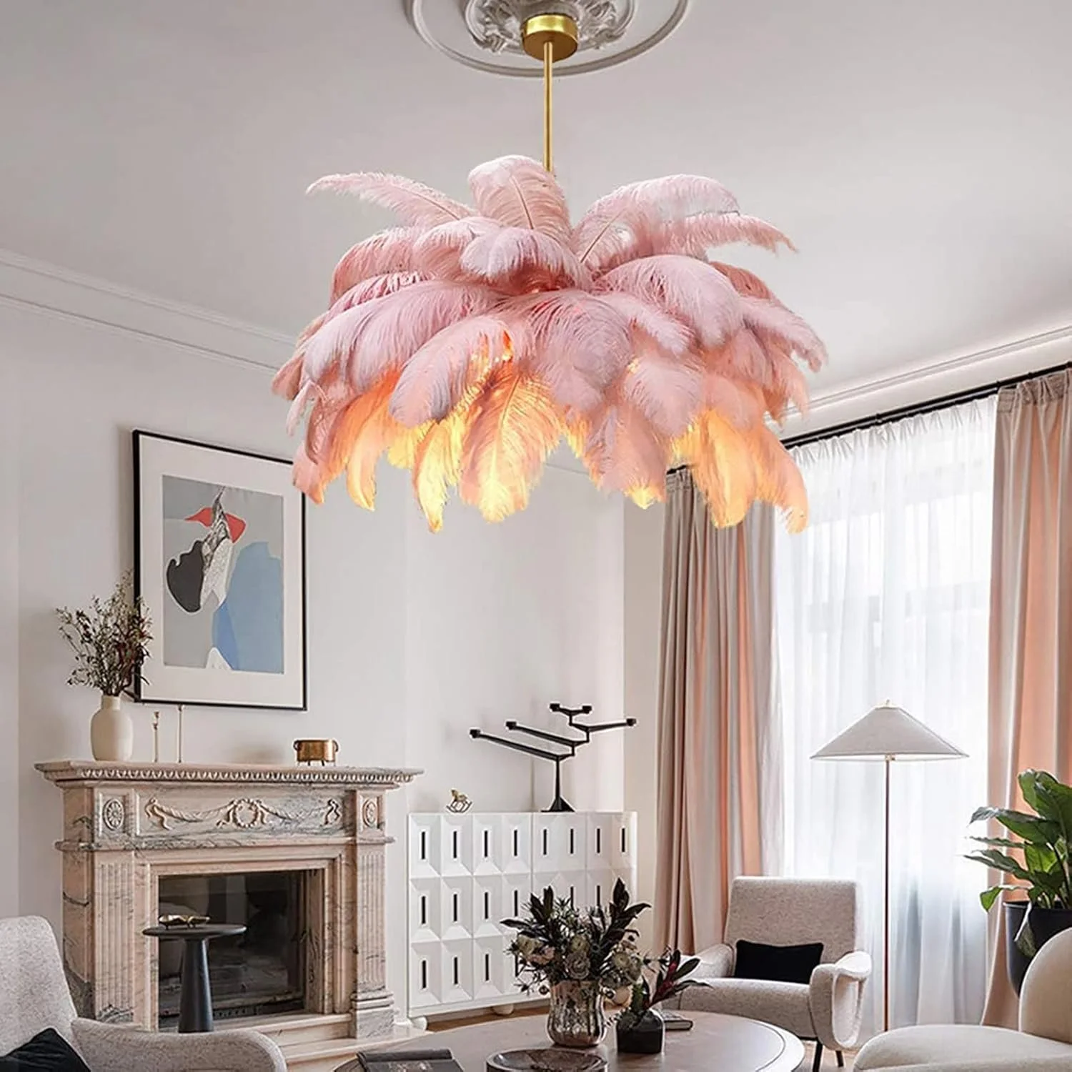 A room with a pink feather chandelier hanging from the ceiling, armchairs, a coffee table with a floral arrangement, curtains, a floor lamp, a framed artwork, and a fireplace.