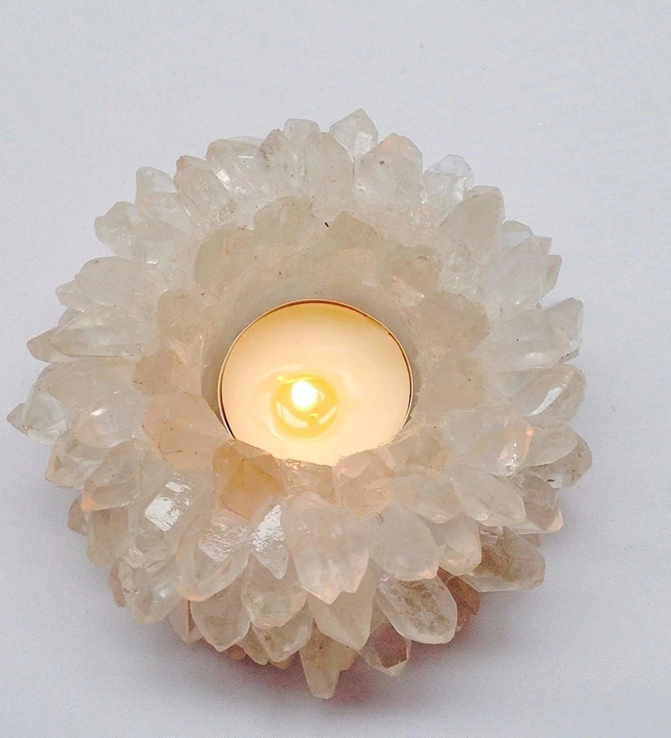 Candle inside a decorative shell-shaped holder with white and translucent crystals.