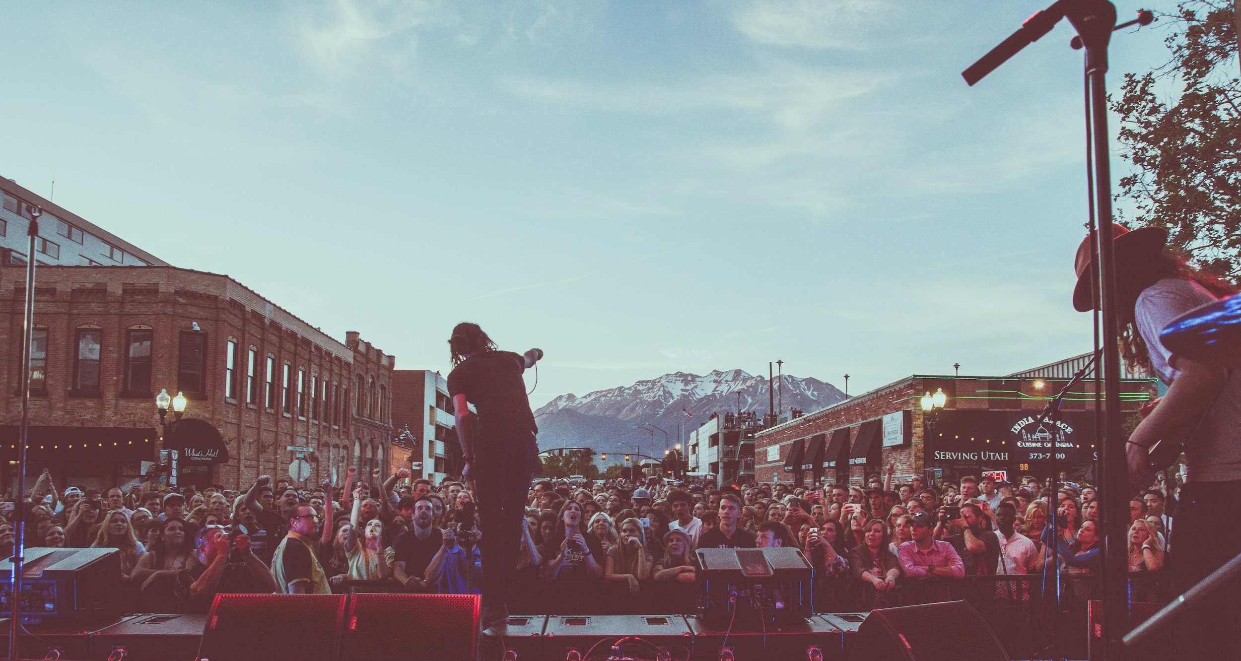 a photo taken from stage showing a crowd of people cheering for a performer who is holding the microphone out toward them