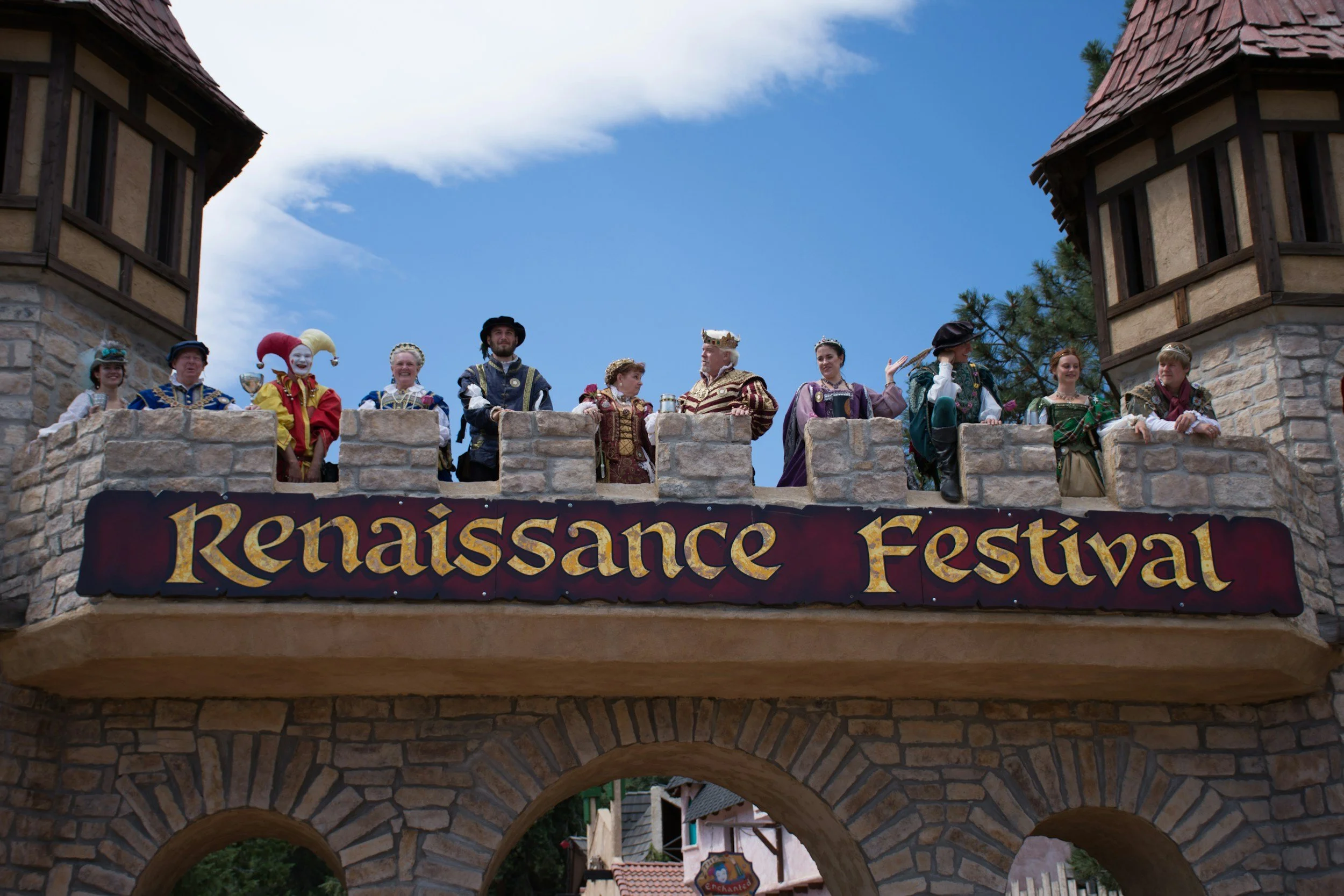 costumed performers standing on a castle turret above a banner that reads 'renaissance festival'