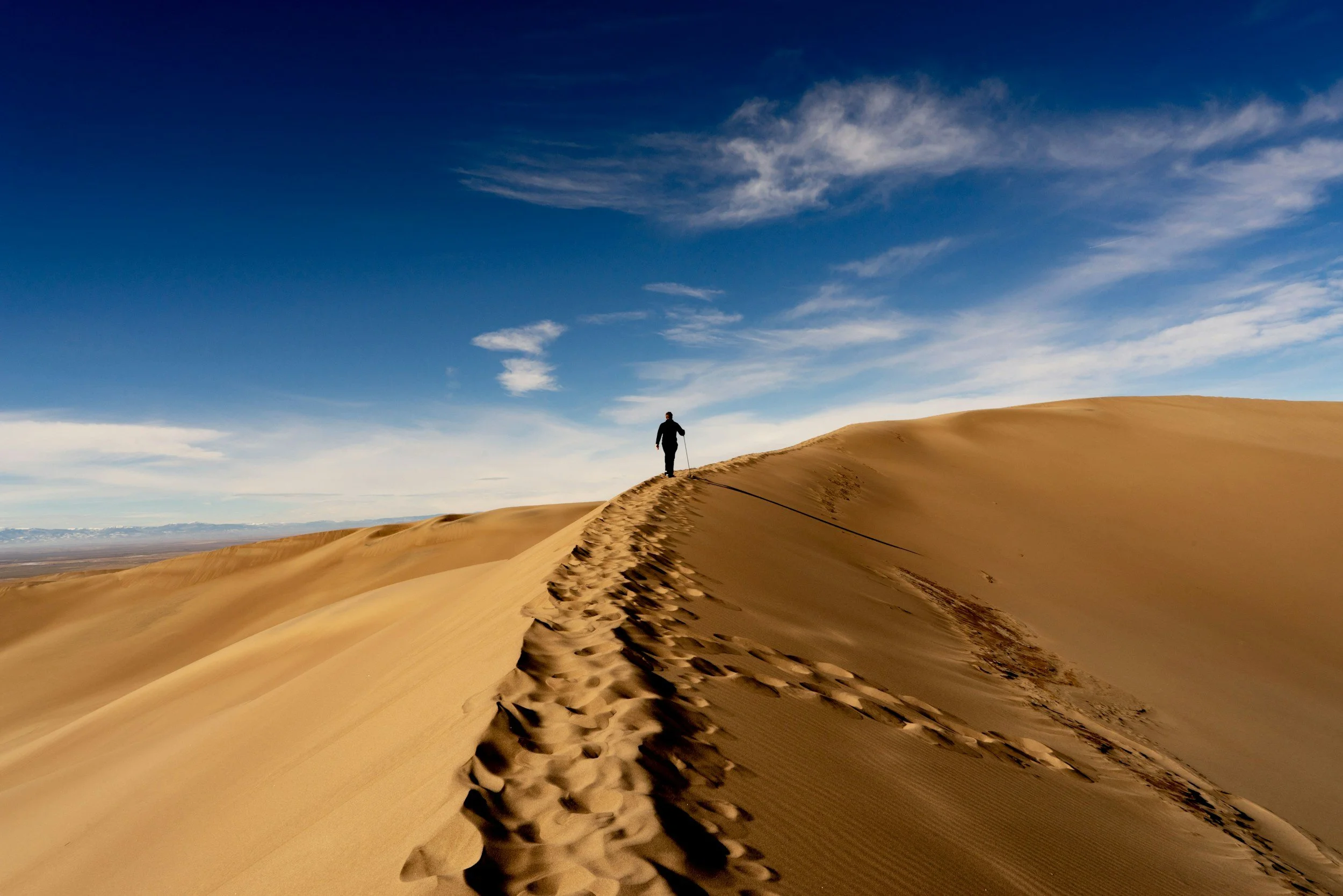 A person walks along the top of a great sand dune