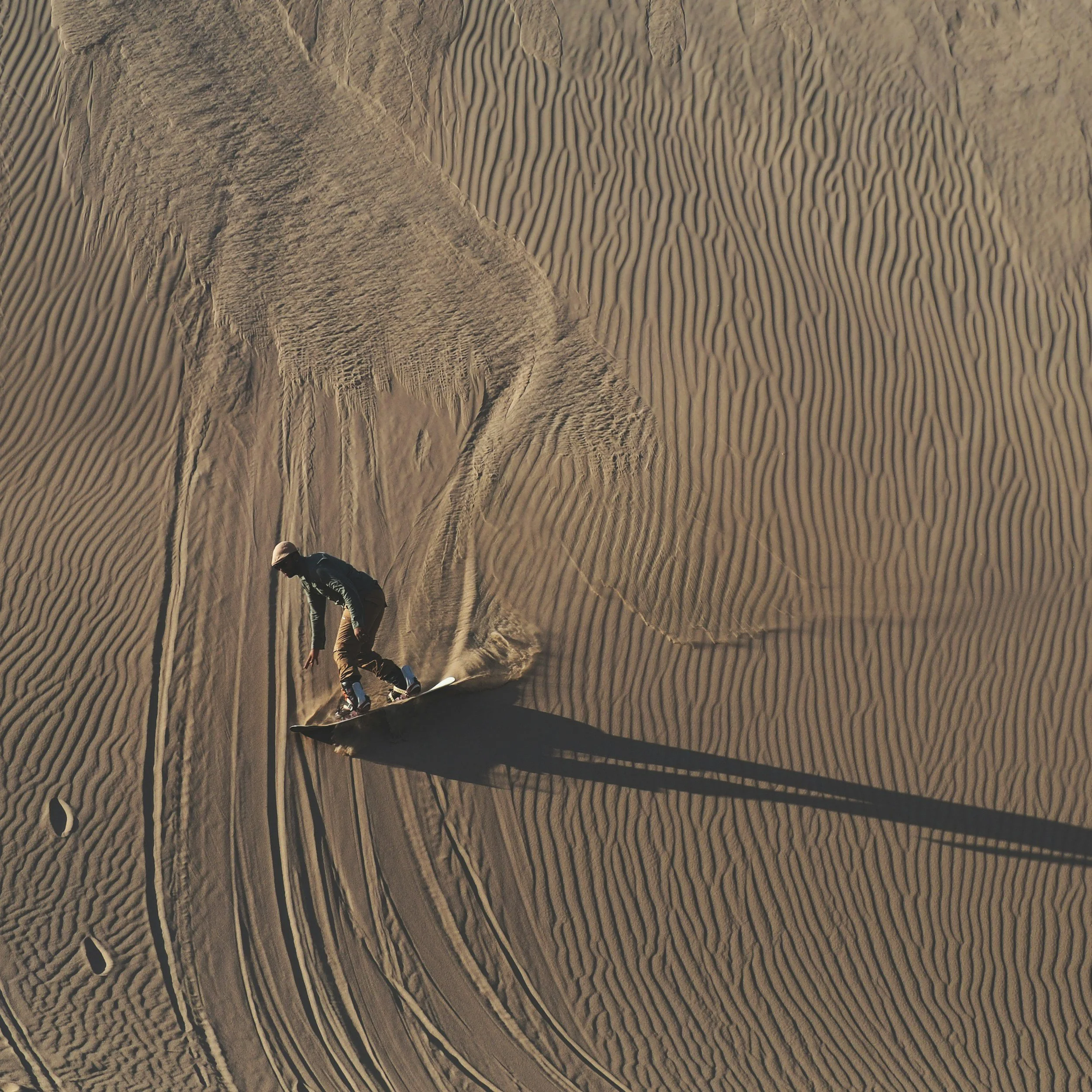A person sand sledding down a great sand dune