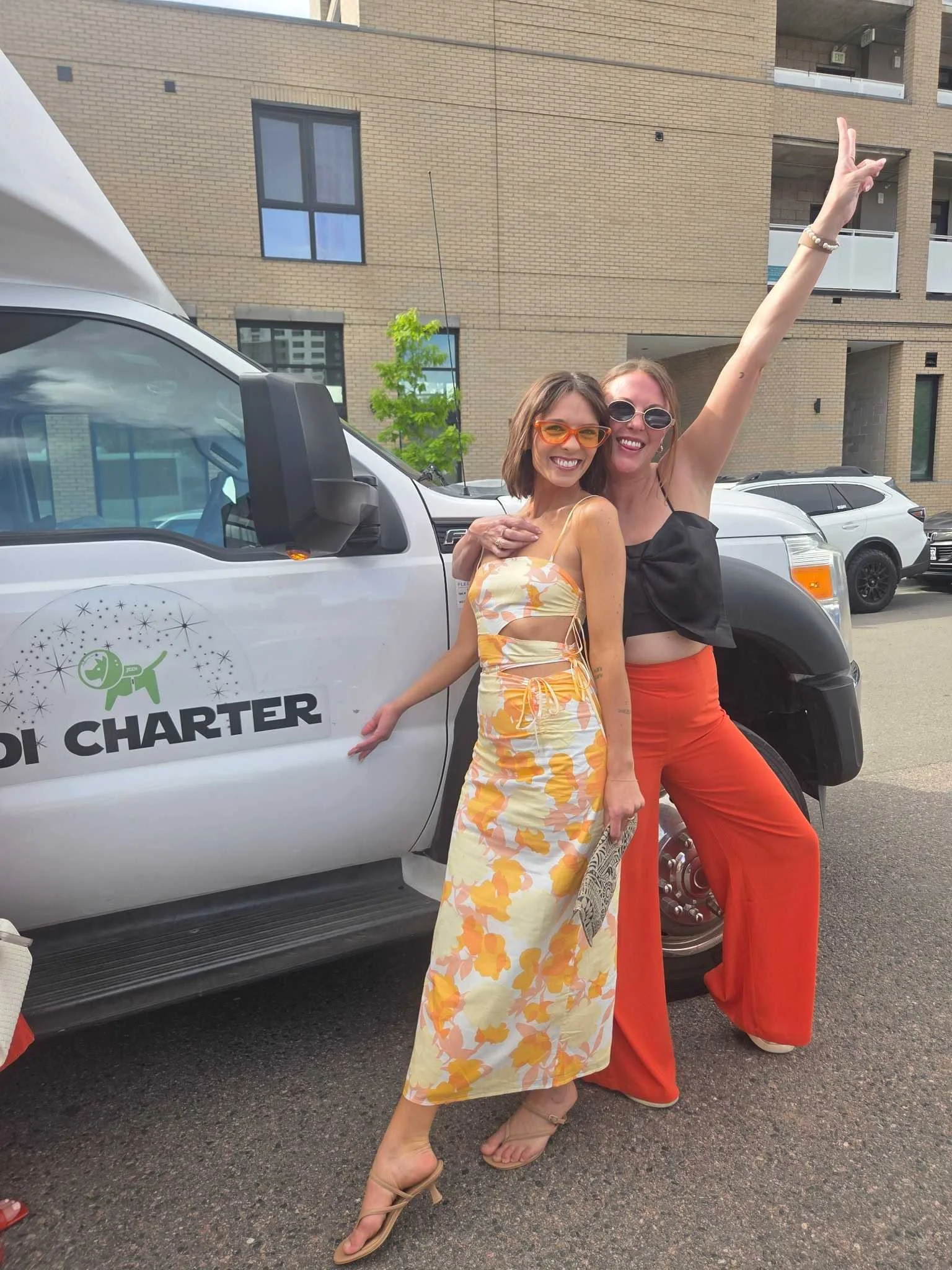 two women celebrate in front of a Jedi Charter Party Bus
