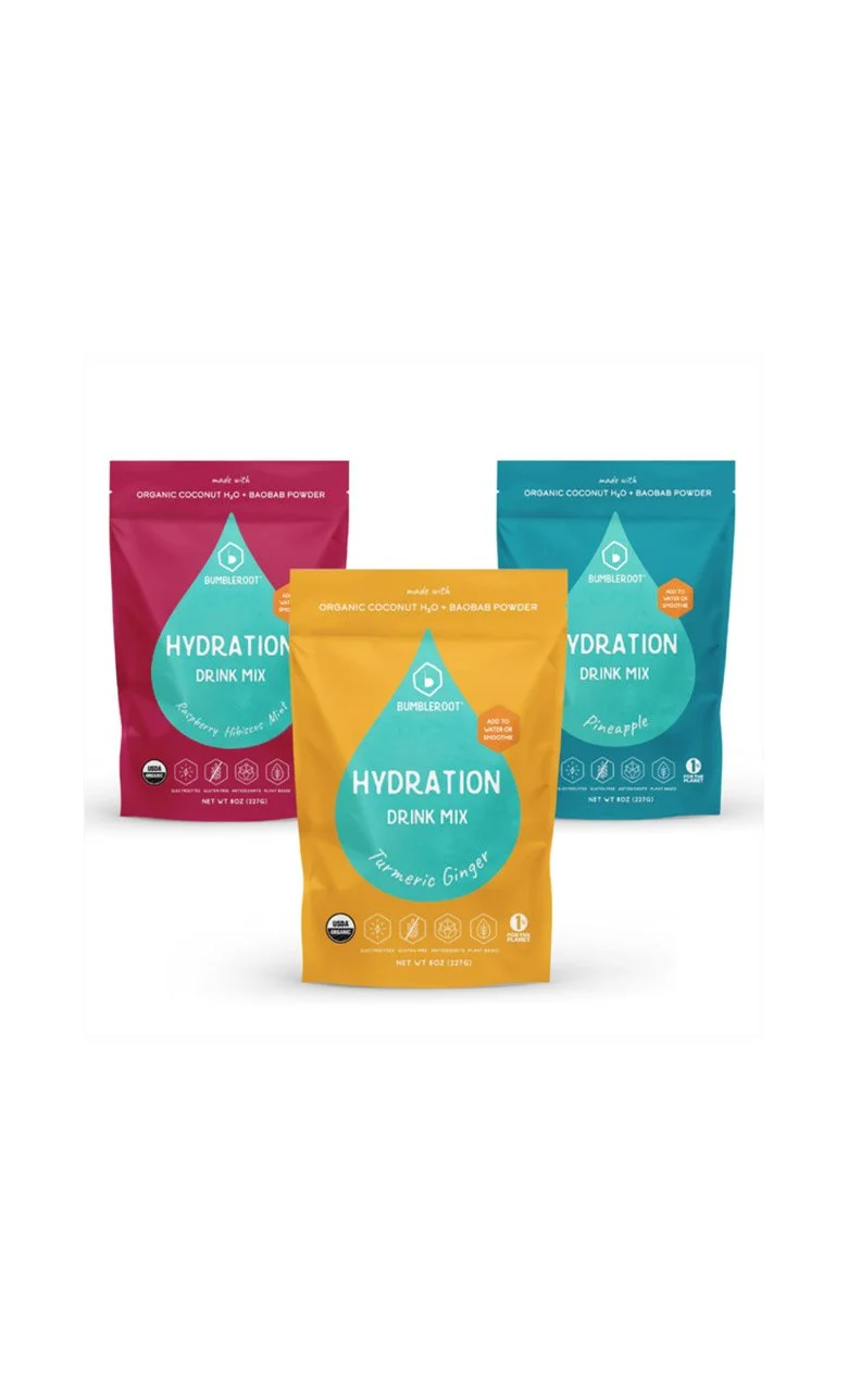 Three packages of Bumbleroot Hydration Drink Mix in flavors Raspberry Hibiscus Mint, Turmeric Ginger, and Pineapple.