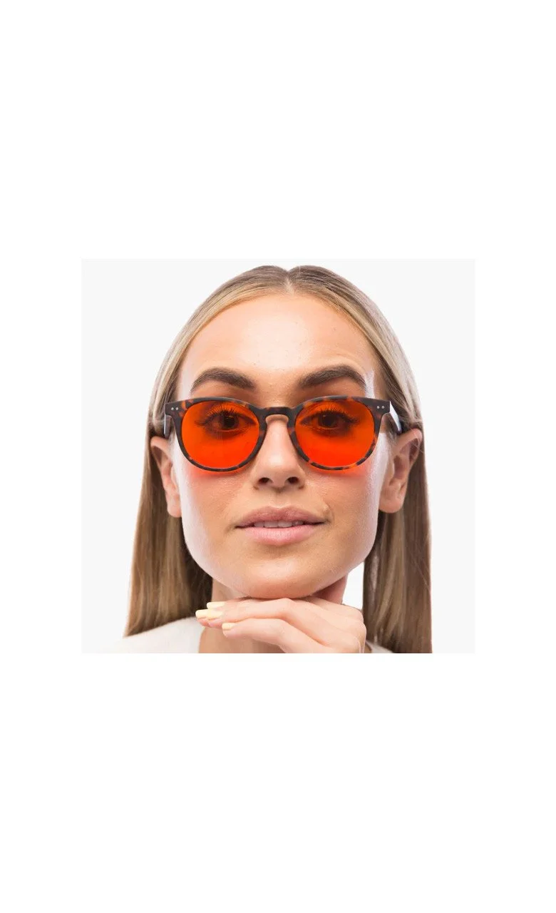 Person wearing orange-tinted sunglasses with light hair and a neutral expression.