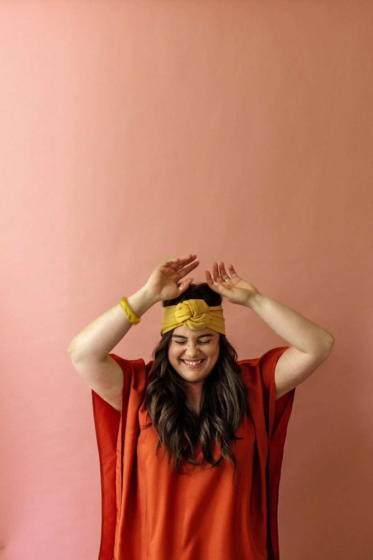 Happy portrait of a woman with a yellow headband and orange tunic.