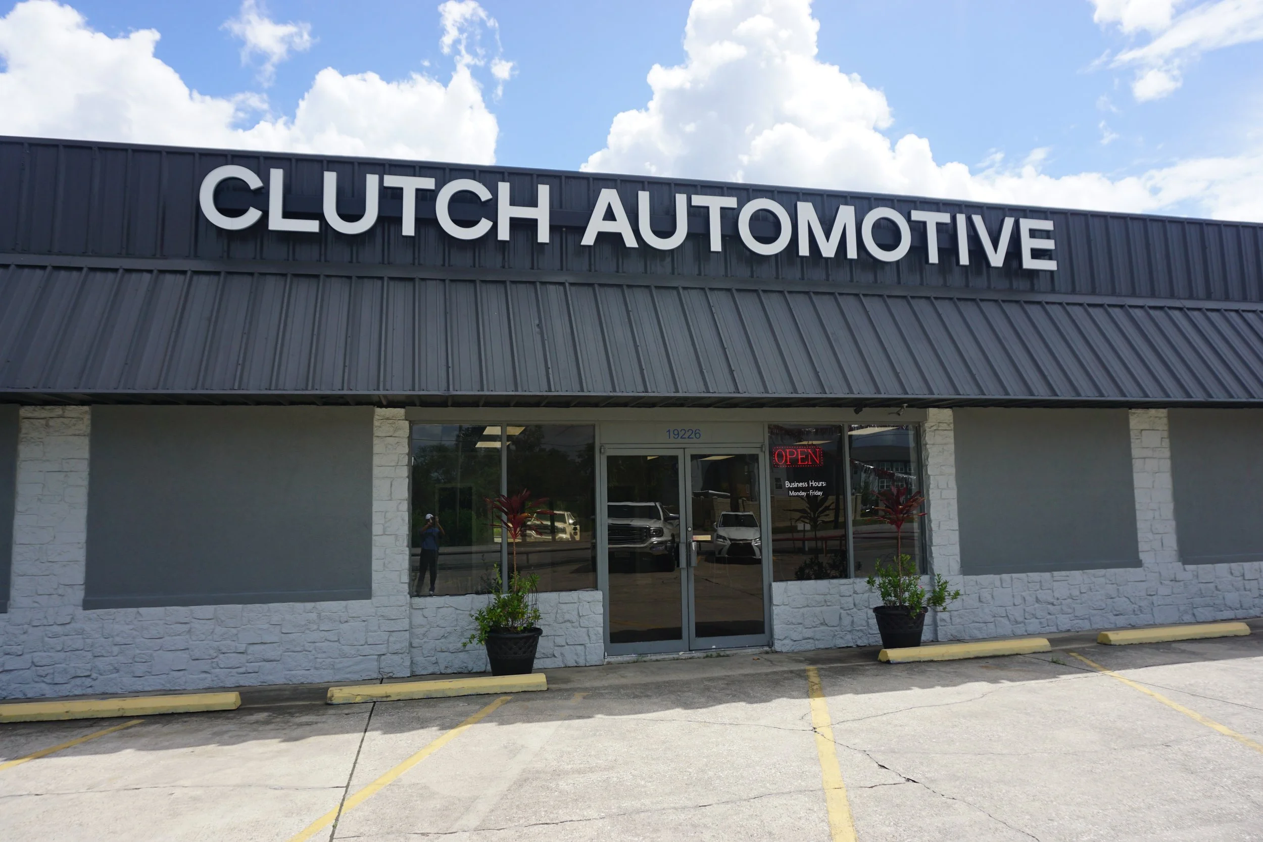 Outside view of Clutch Automotive building with signage, parking lot, and a small sidewalk.