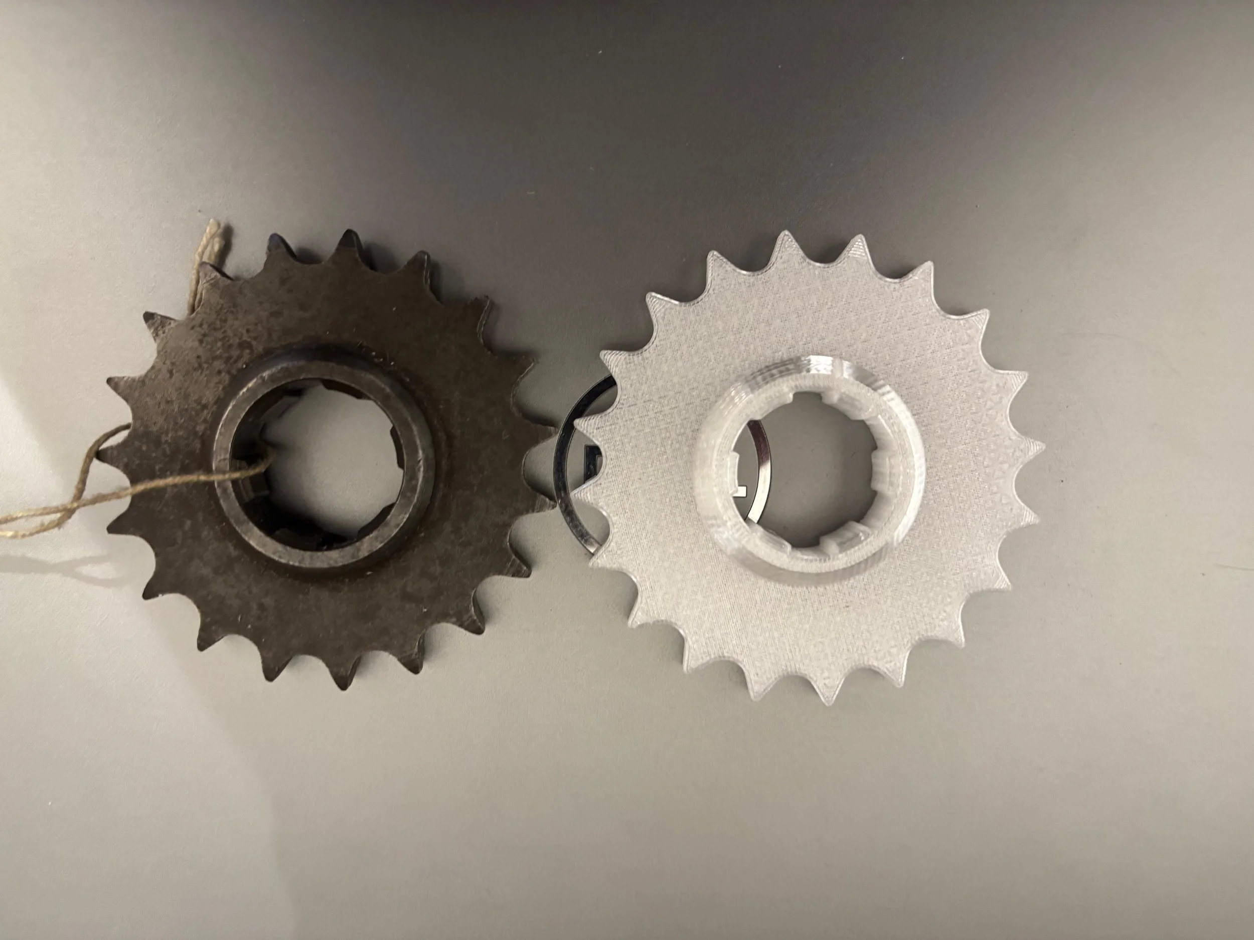 An original, worn motorcycle sprocket alongside a 3D‑printed PETG replica used as a physical reference before machining a new replacement. The obsolete sprocket was measured and modelled in CAD, then printed to verify tooth geometry, offsets and clea