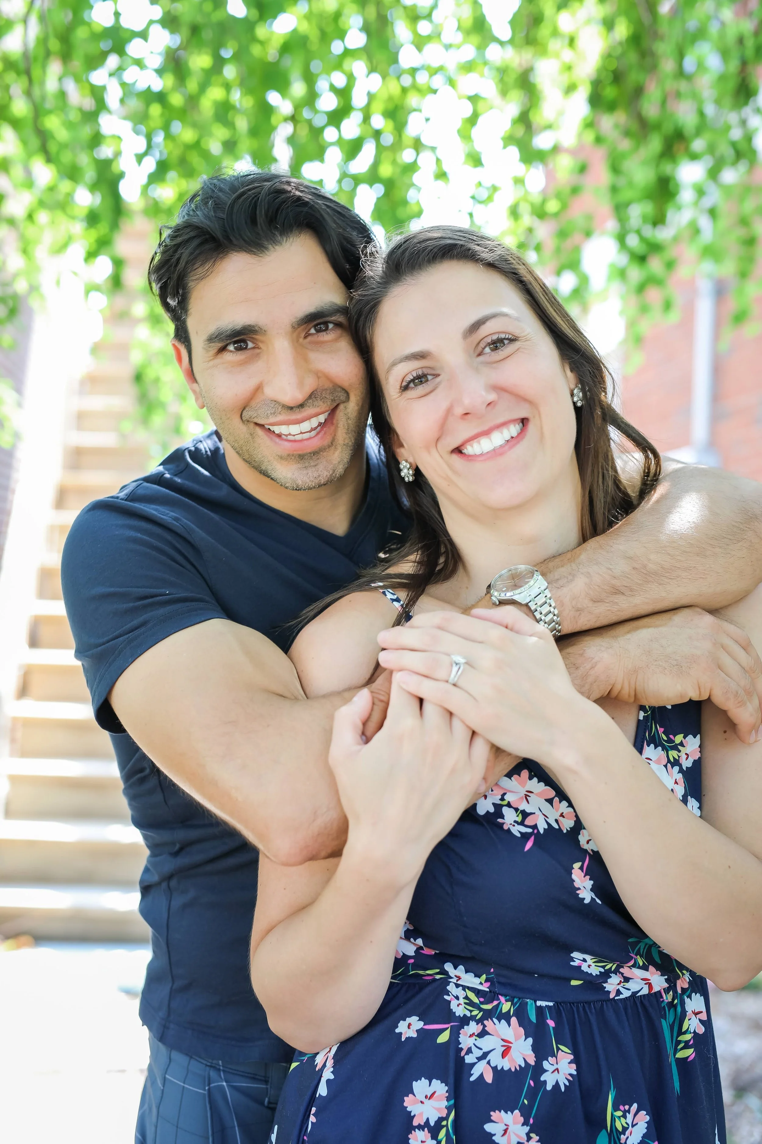 Hosts Samantha and Scott at Rocky Heart Hideaway chalet in Grand Lake, CO, posing outdoors with greenery in the background.