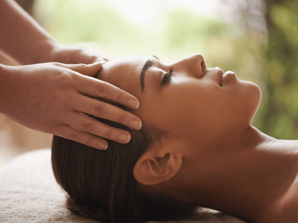 A woman receiving a head massage in a relaxing environment.