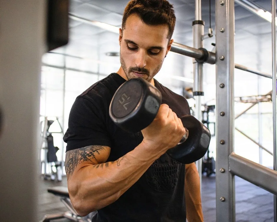 Man lifting a dumbbell in a gym.