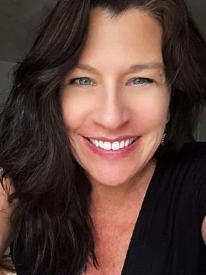 Close-up of a smiling woman with long dark hair and blue eyes