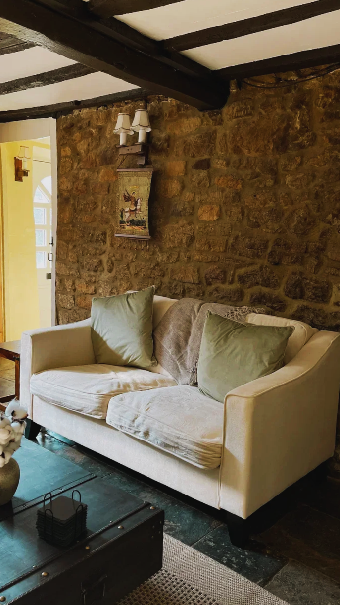 A comfortable lounge seating area in The Dun Cow, set against an exposed stone wall and dark ceiling beams.