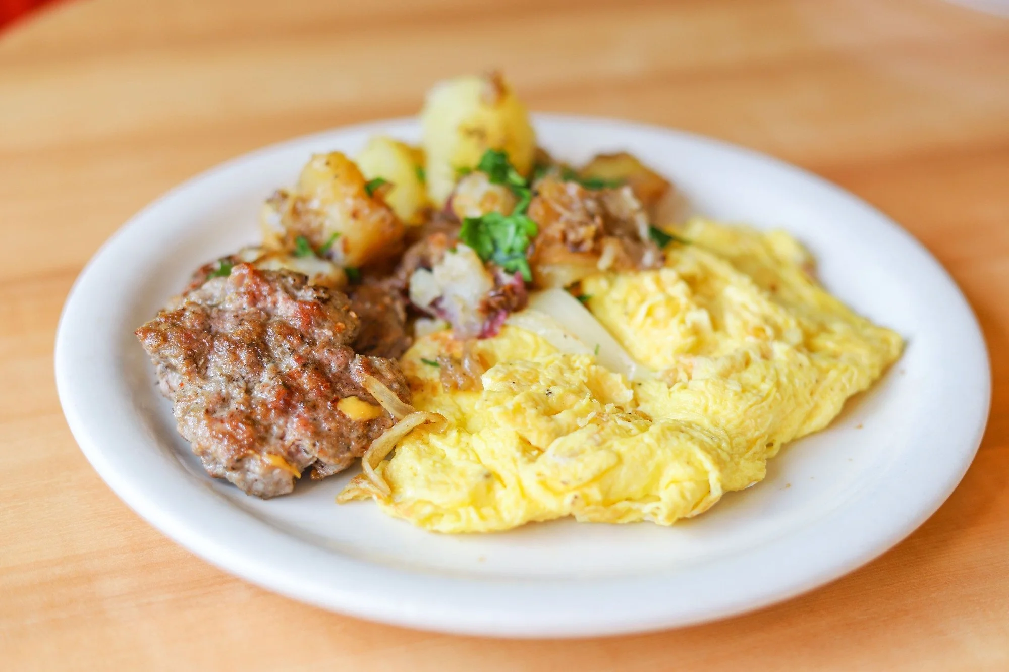 Two cage-free scrambled eggs, two house made breakfast sausages, and house potatoes with herbs.