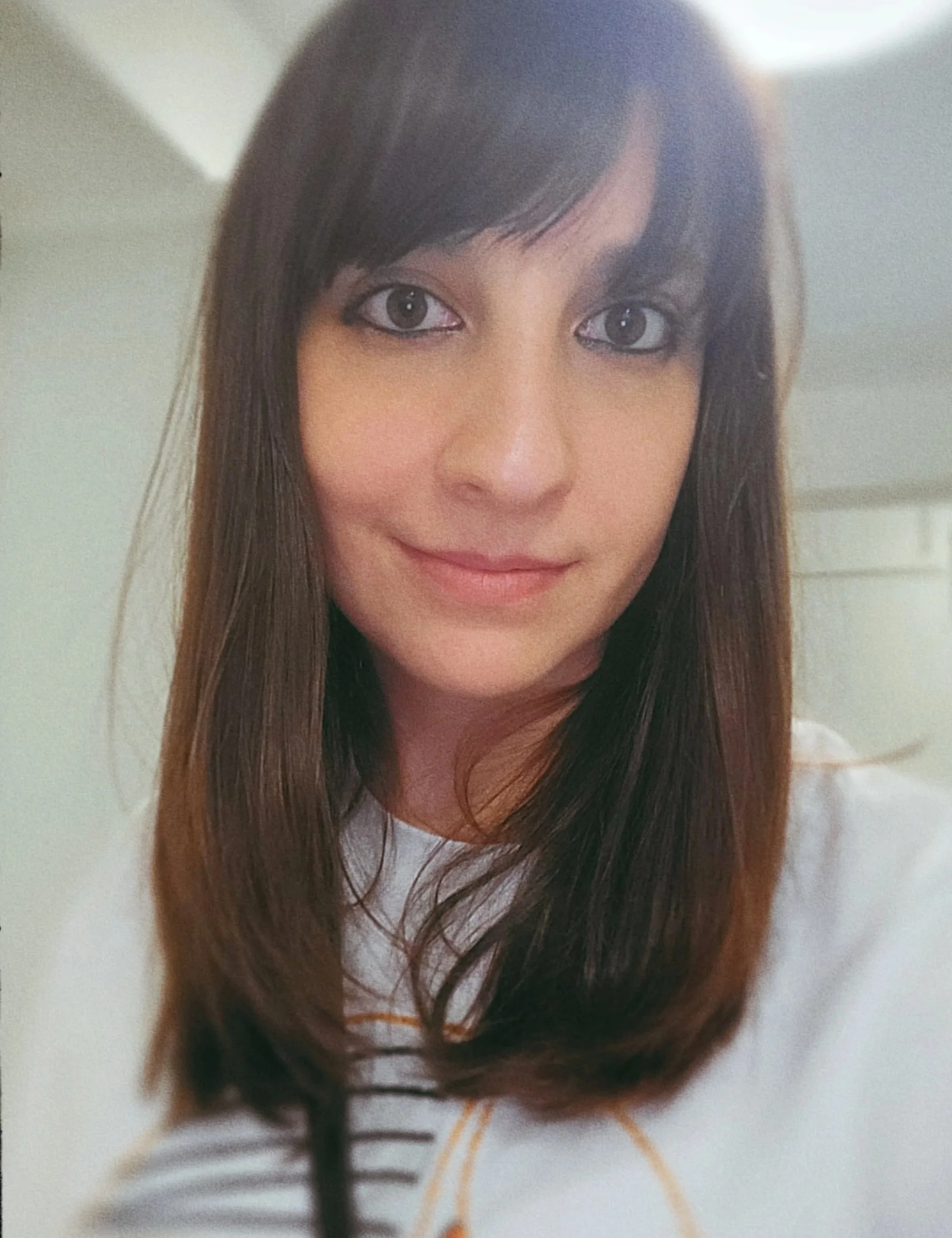 A close-up photograph of Dominique: she has brown hair and brown eyes and is smiling at the camera.