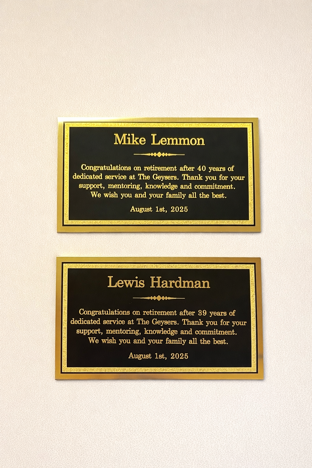 Two retirement plaques on a light-colored wall. The top plaque is for Mike Lemmon, celebrating 40 years of service, dated August 1, 2025. The bottom plaque is for Lewis Hardman, celebrating 39 years of service, also dated August 1, 2025.