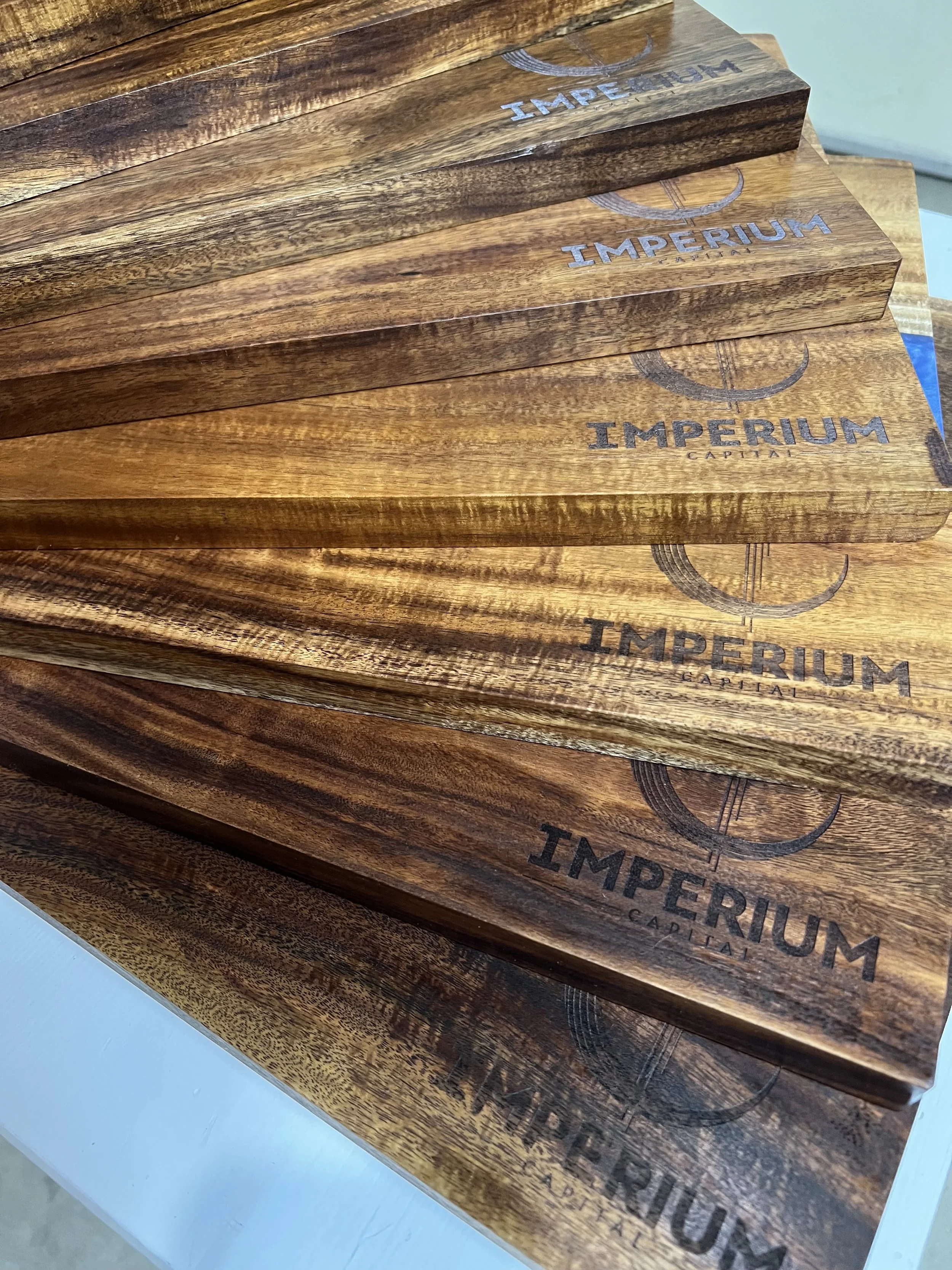 Stack of wooden plaques with the Imperial Capital logo and branding printed on them.