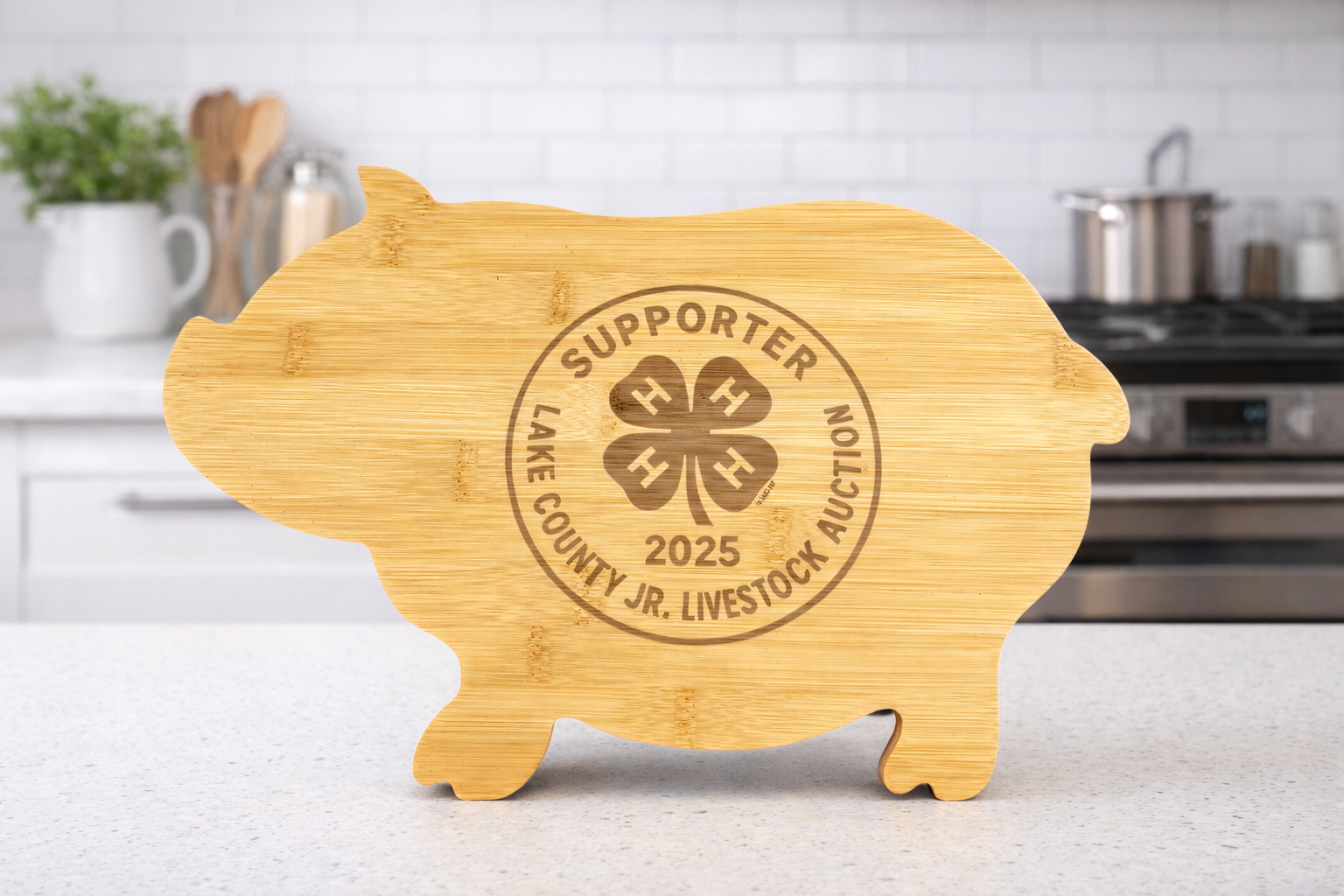 A wooden pig-shaped sign with the words 'Supporter Lake County Jr. Livestock Auction 2025' and a four-leaf clover logo, placed on a kitchen countertop.