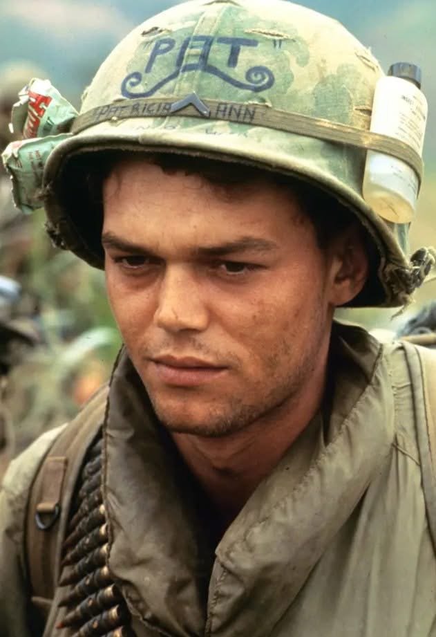 A soldier wearing a helmet with the word "PFT" written on it, looking serious, with a background suggesting a military setting.