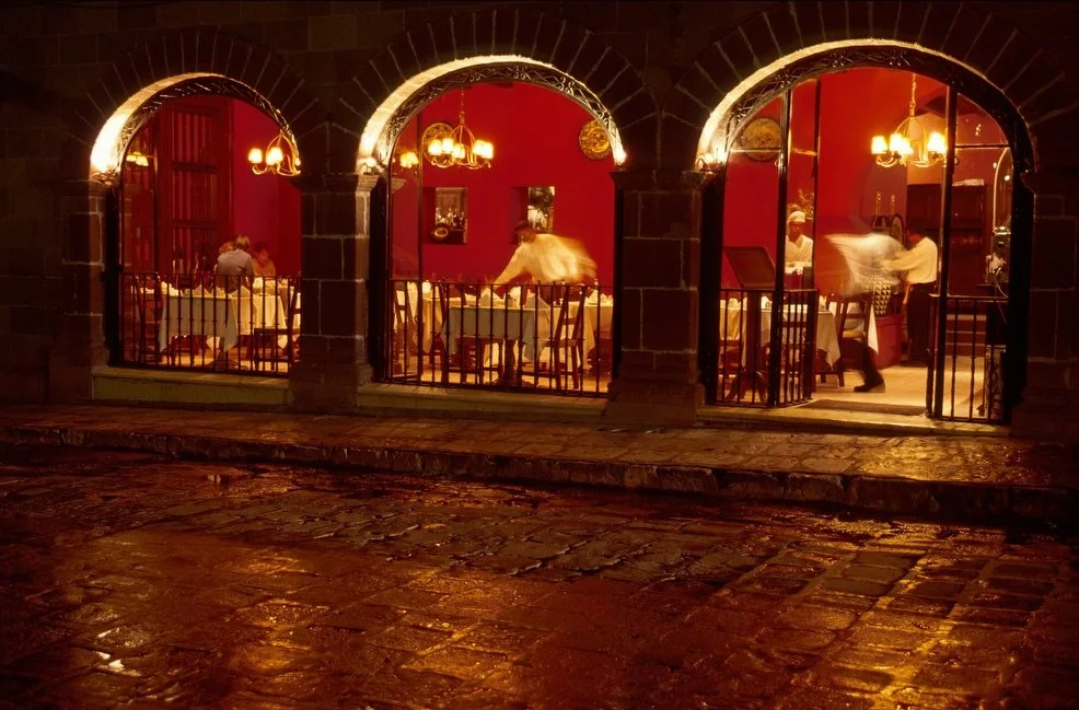 The Restaurant.
.
I captured this image of swirling motion in the arches of this restaurant in San Miguel de Allende, Mexico. I love the curves of the arches, the rich red color, the movement of the waitstaff, and the light of the reflection on the f