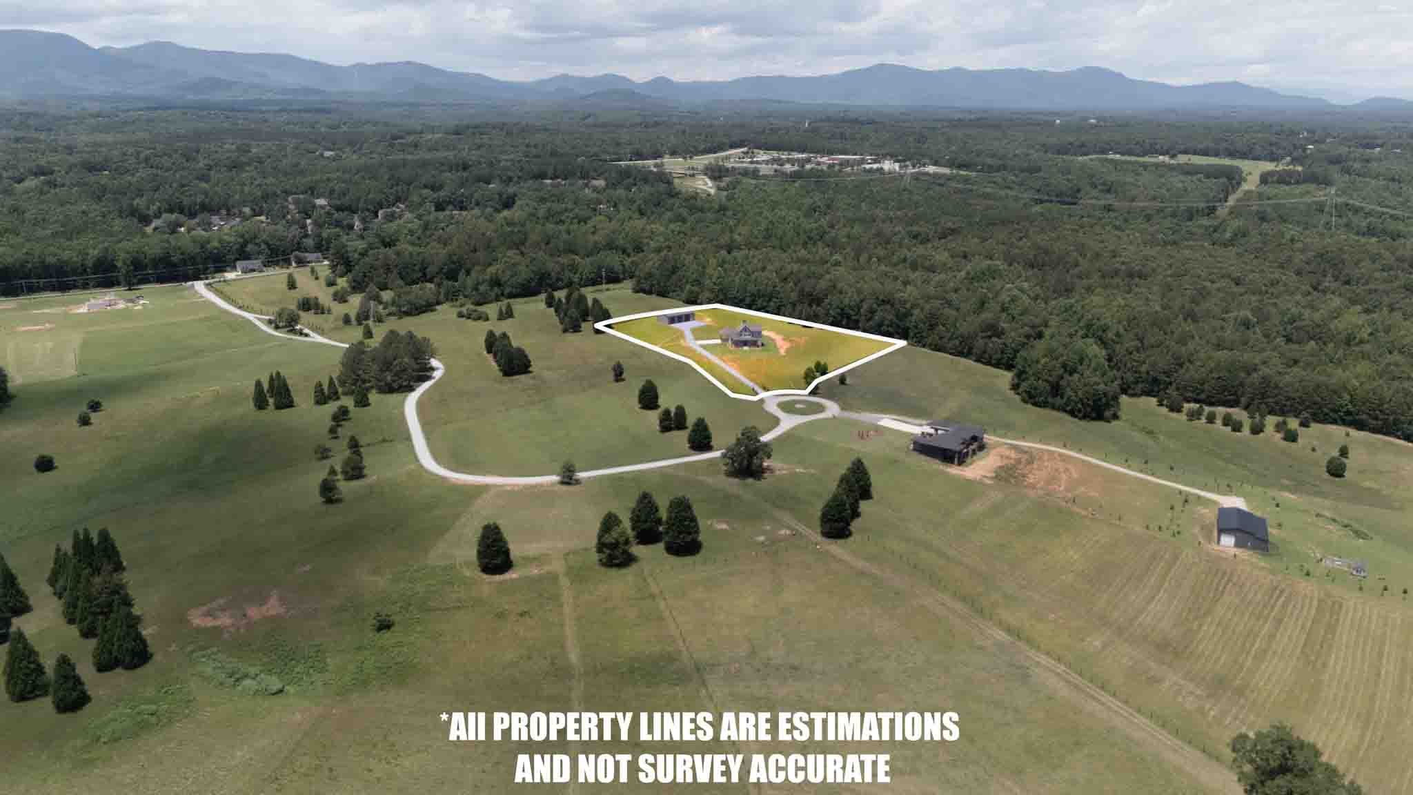 Aerial view of a large rural property with a house, outbuildings, and surrounding land outlined with white property lines, with a forested area in the background and mountains in the distance. Text on the image states that property lines are estimati