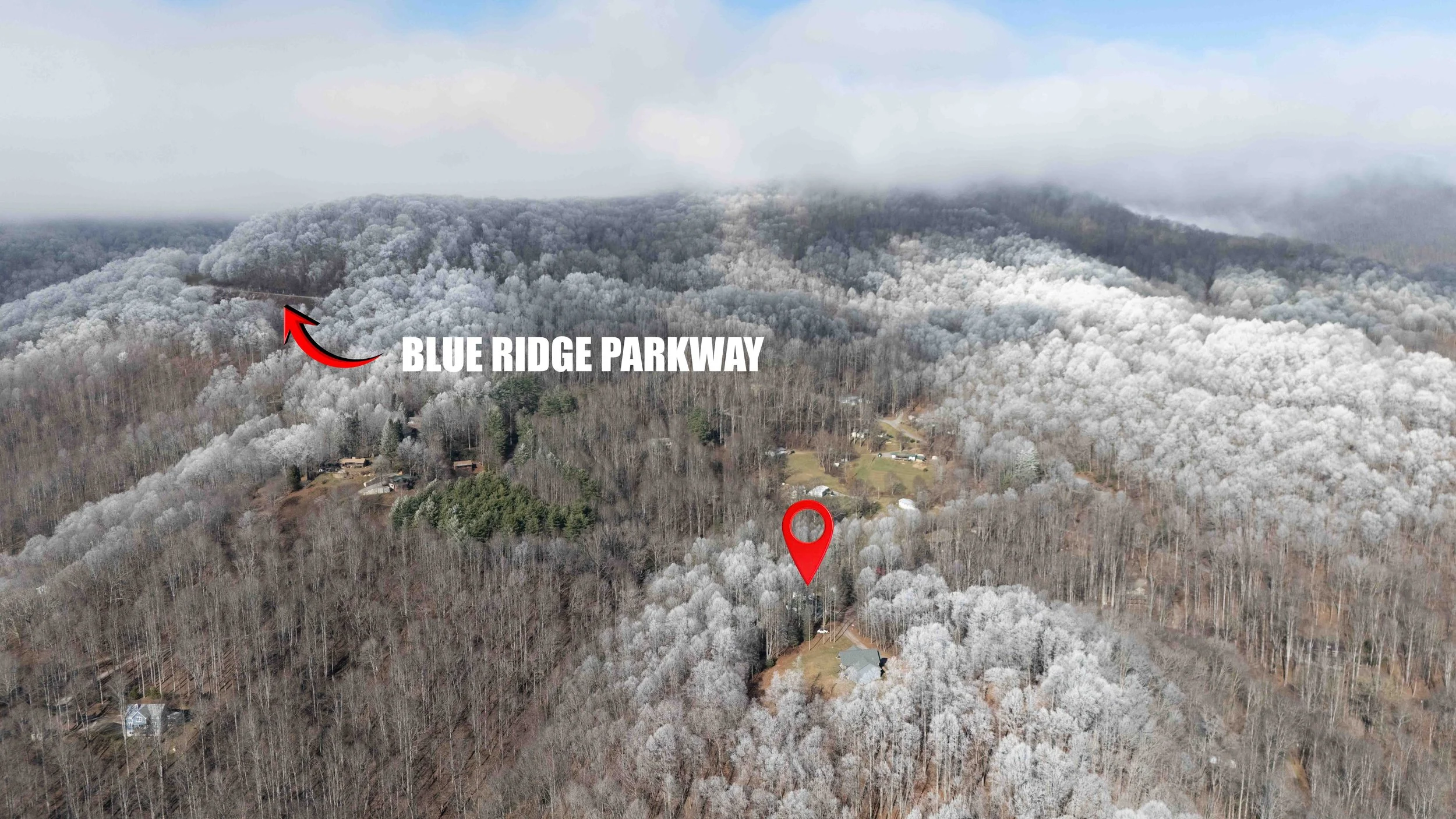 Aerial view of a forested hillside with snow-covered trees, labeled with 'Blue Ridge Parkway' and a red location pin marking a specific house or building among the trees.