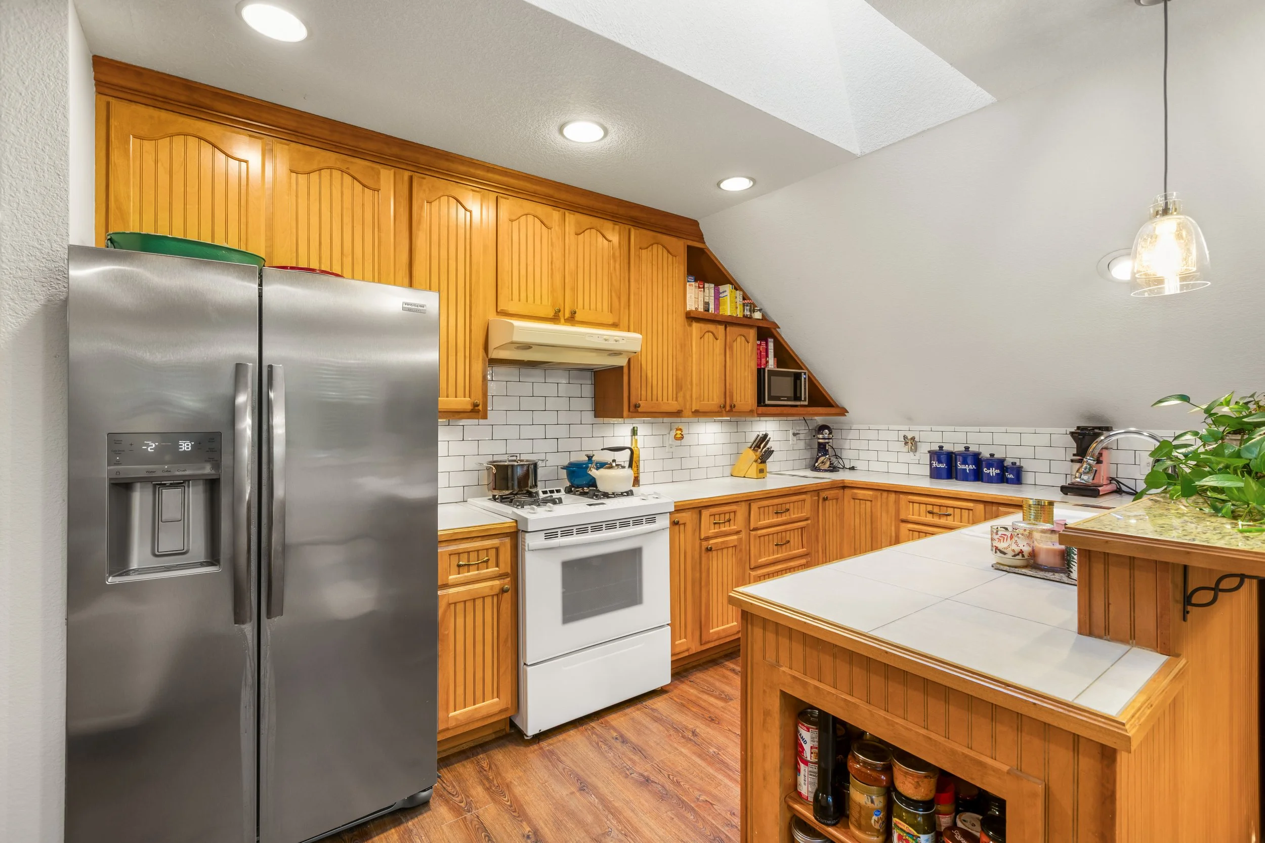 kitchen with wooden cabinets, white stove, stainless steel refrigerator, white tile backsplash, and various kitchen appliances and utensils