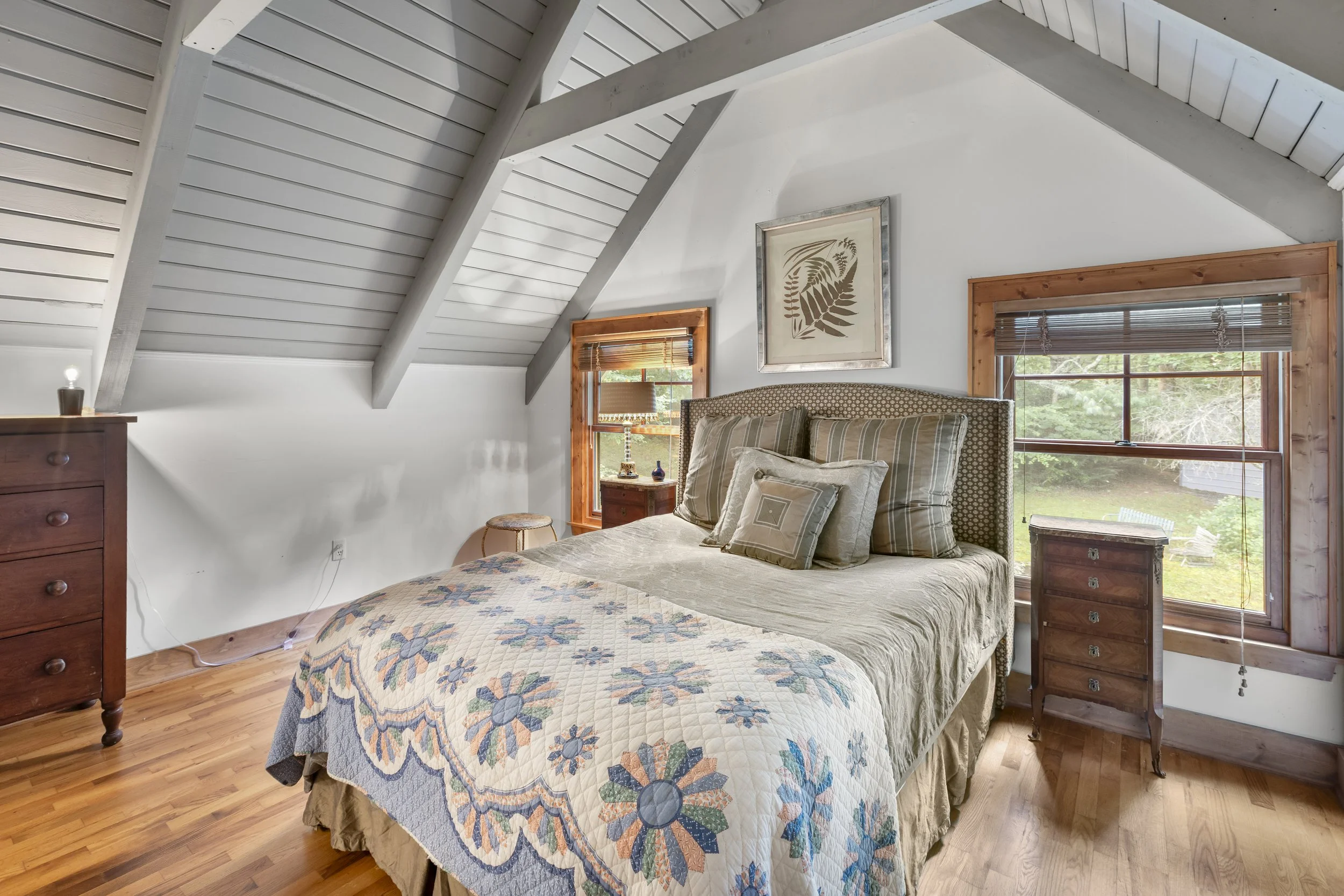 Cozy bedroom with a bed, wooden furniture, window, and artwork on the wall.