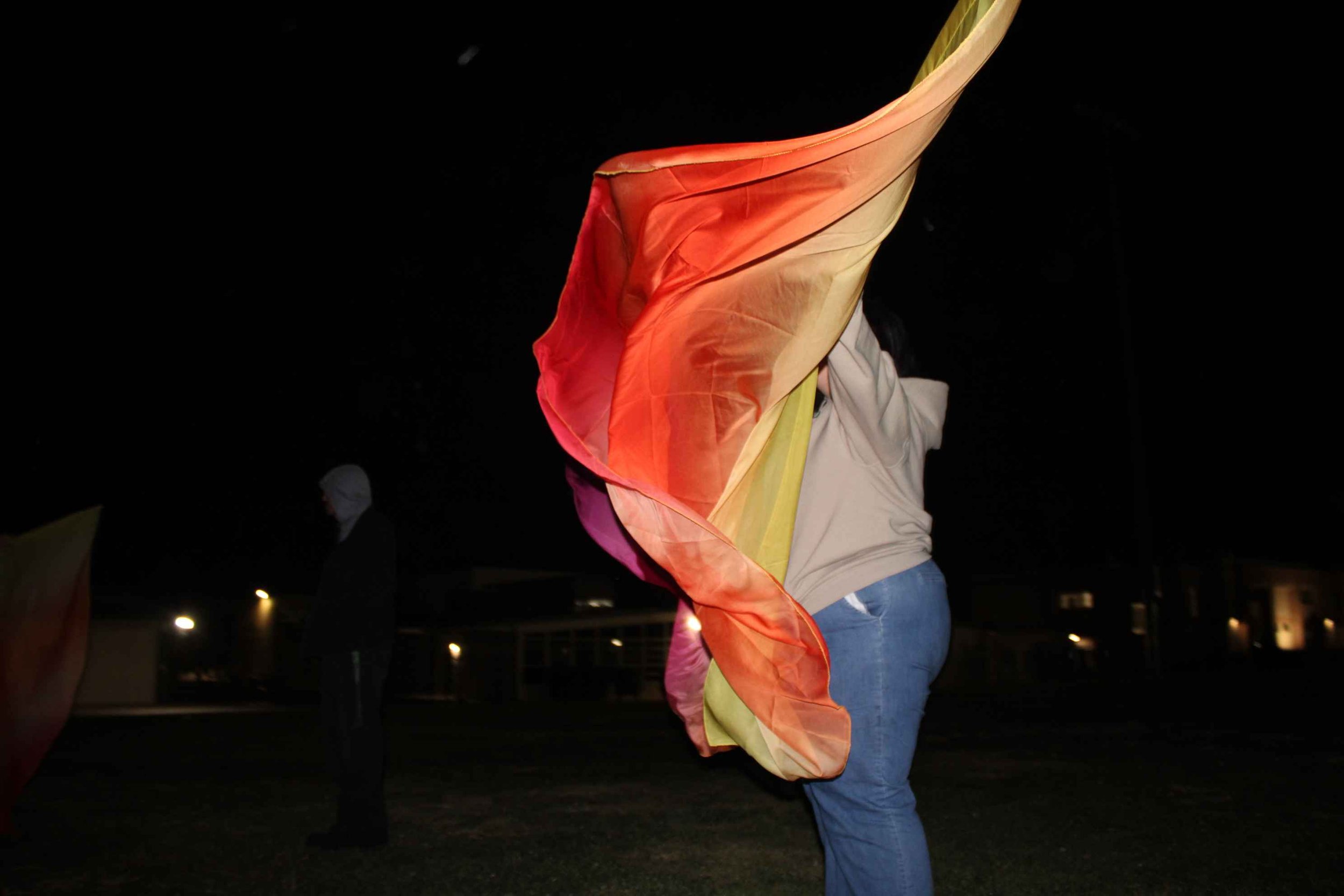 Person waving a rainbow-colored flag outdoors at night