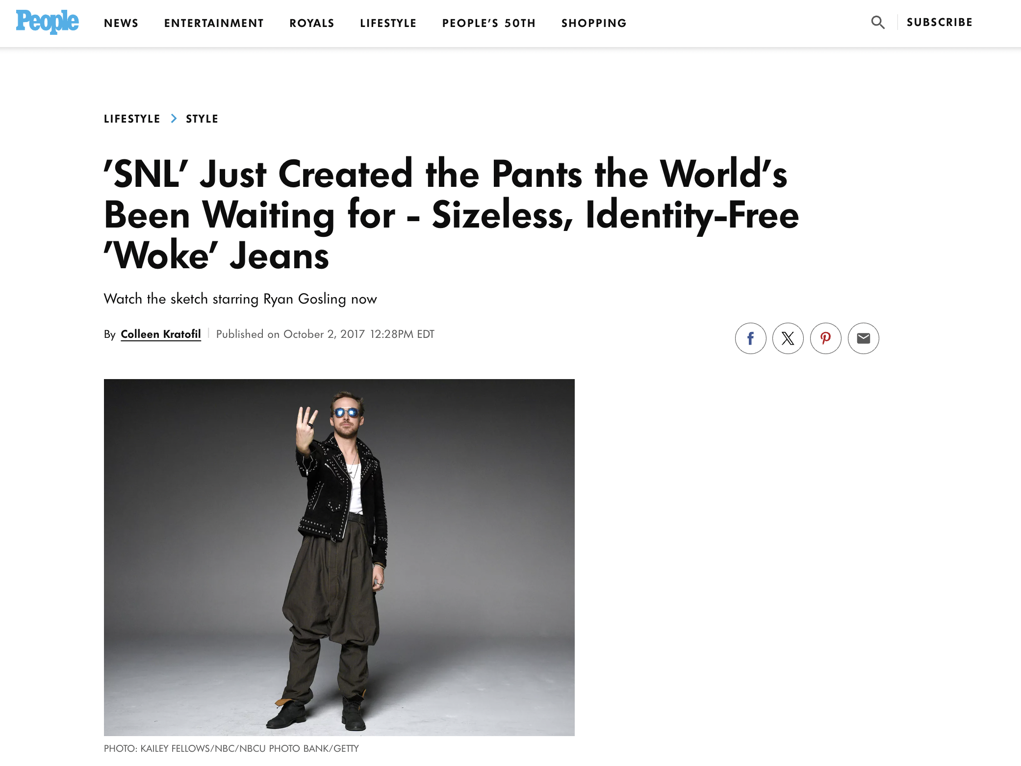 A man dressed in a hip-hop style outfit with baggy pants, a jacket, and sunglasses, standing against a gray background and holding up three fingers.