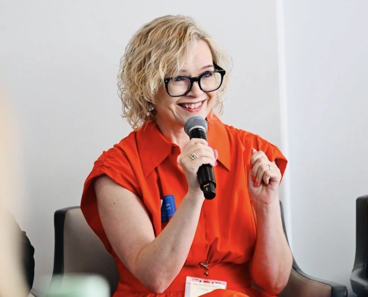 Luan Lawrenson-Woods wearing a red dressing holding a microphone and talking