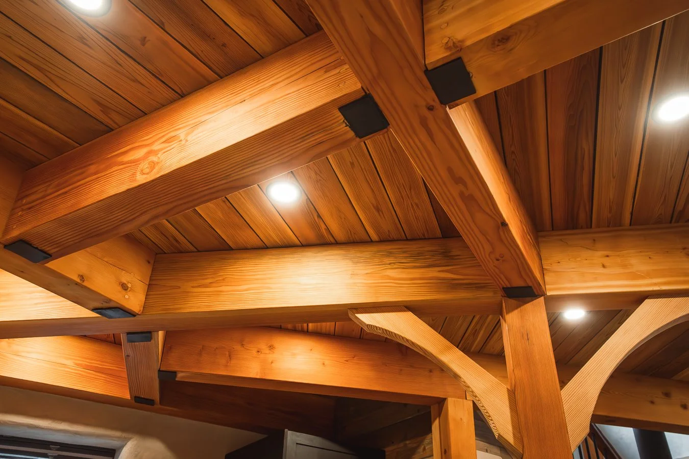 Close-up view of a wooden ceiling with large beams and spotlights.