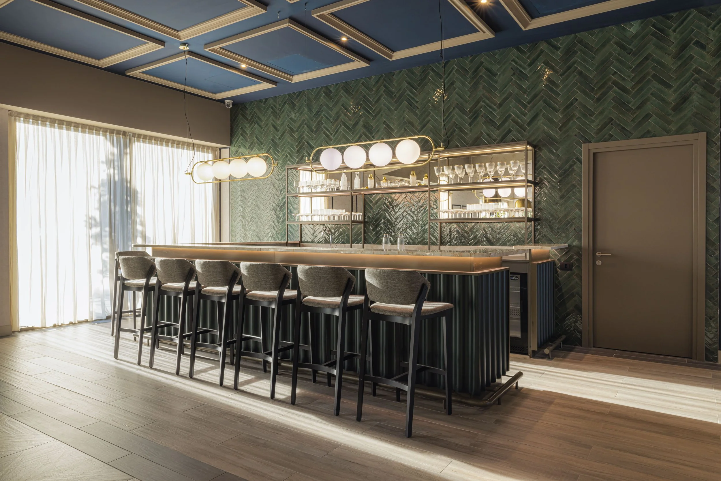 Un bar elegante con sgabelli davanti a un bancone, decorazione moderna e luce soffusa.