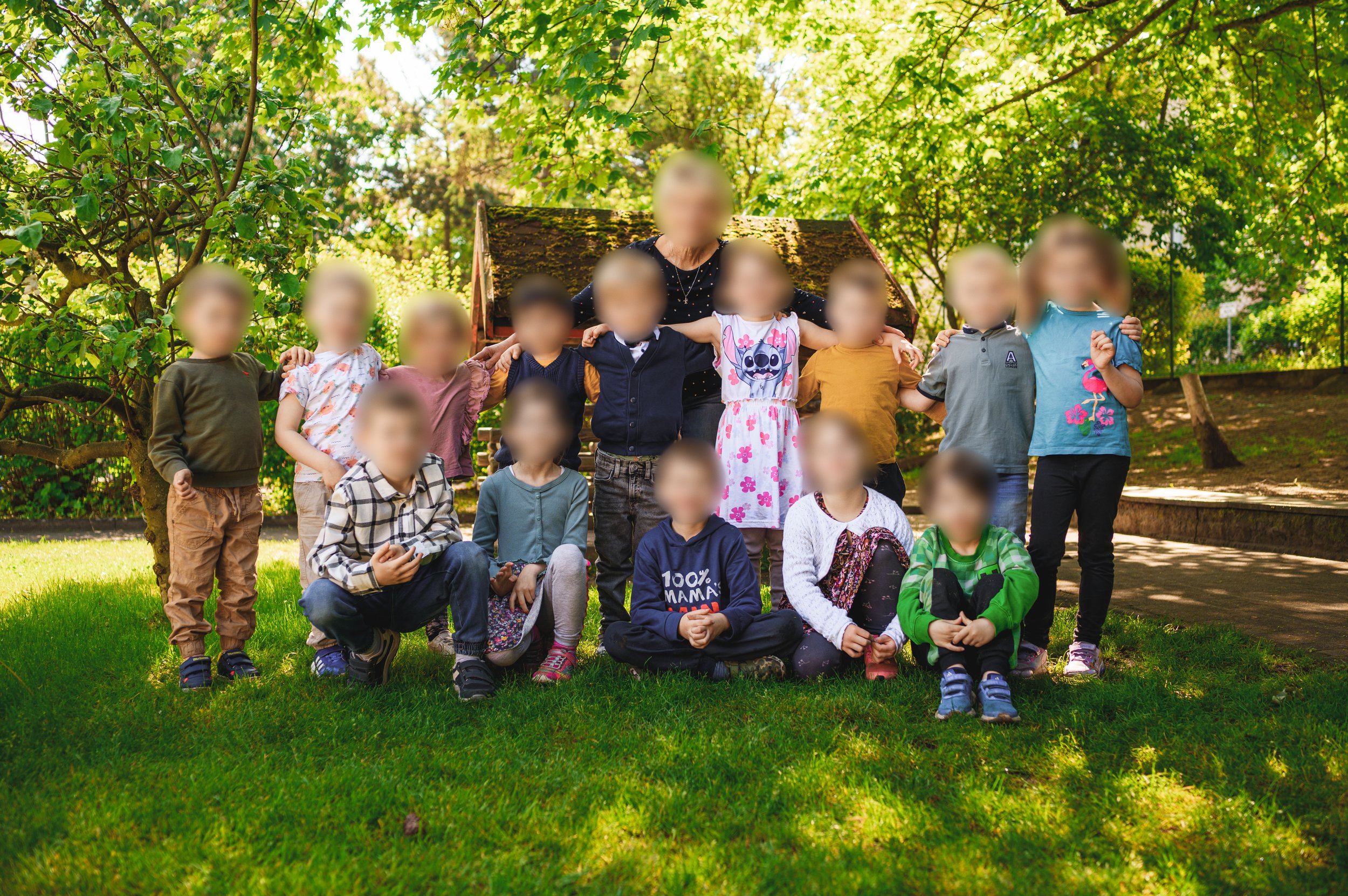 Modernes Kita-Gruppenfoto auf der Wiese mit lockerer Anordnung und natürlicher Atmosphäre.