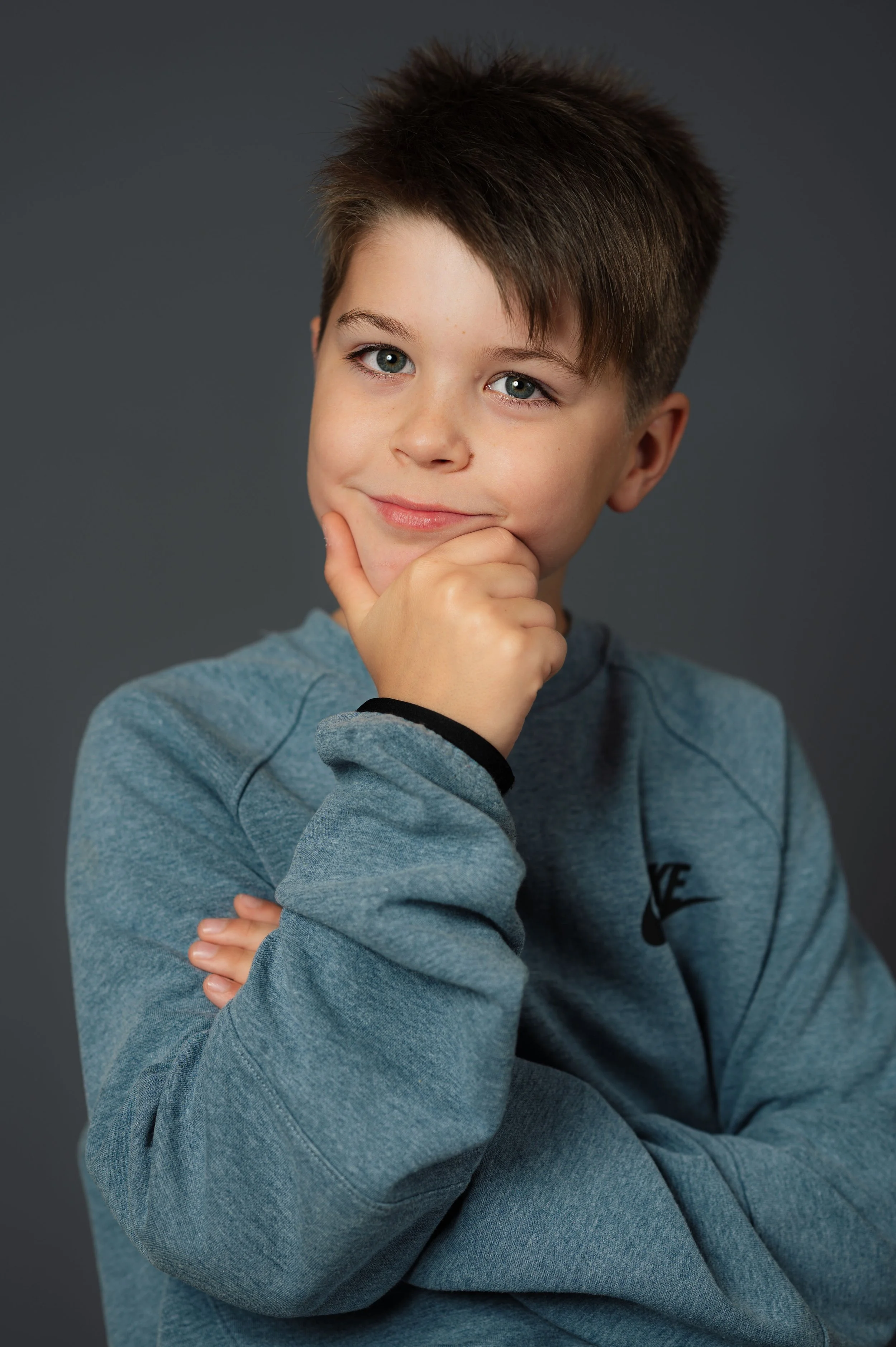 Studio-Porträt eines Schülers vor neutralem grauen Hintergrund in moderner Schulfotografie.