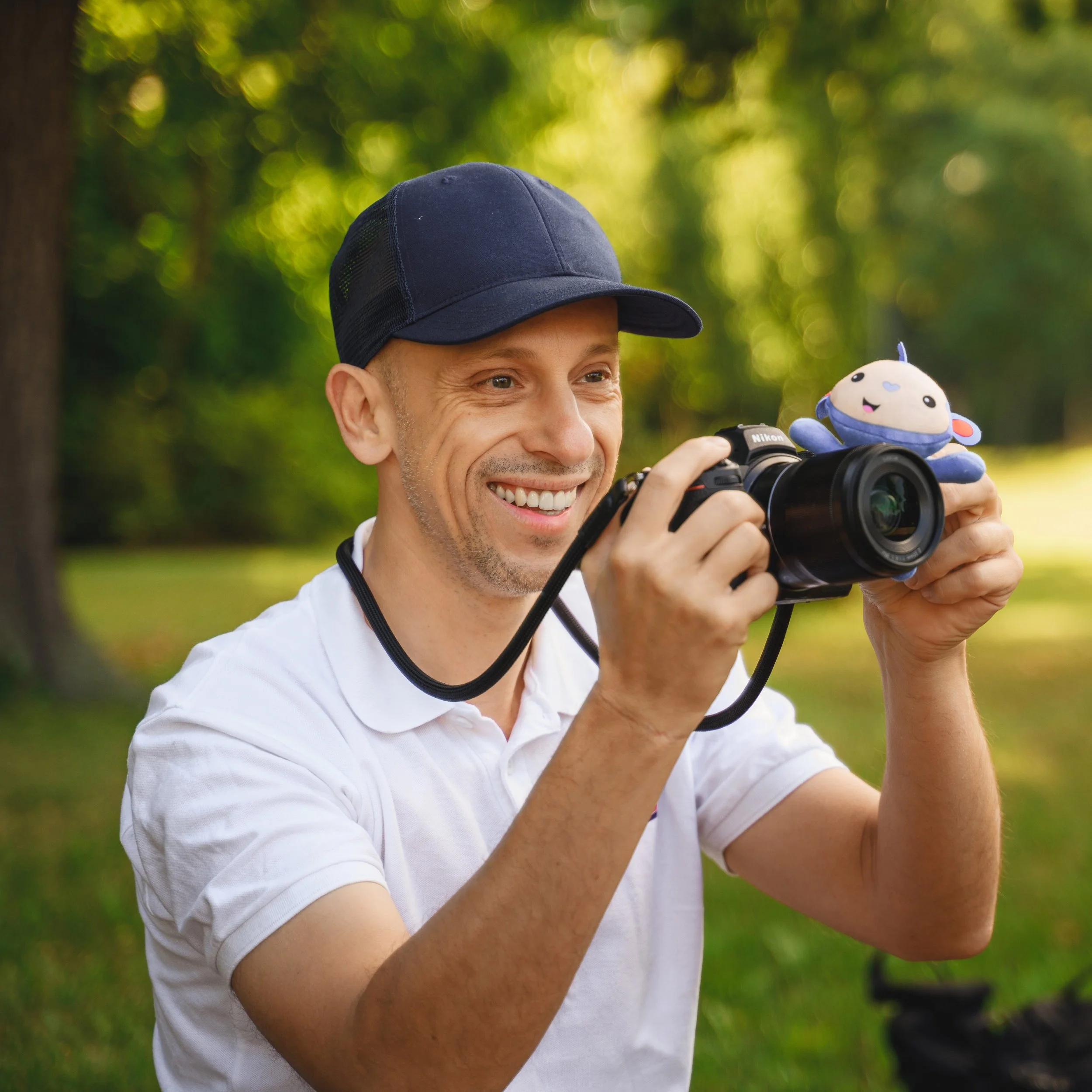 Kinderfotograf Ron Marzok lächelt mit seiner Kamera und dem kleinen Affen Fips.