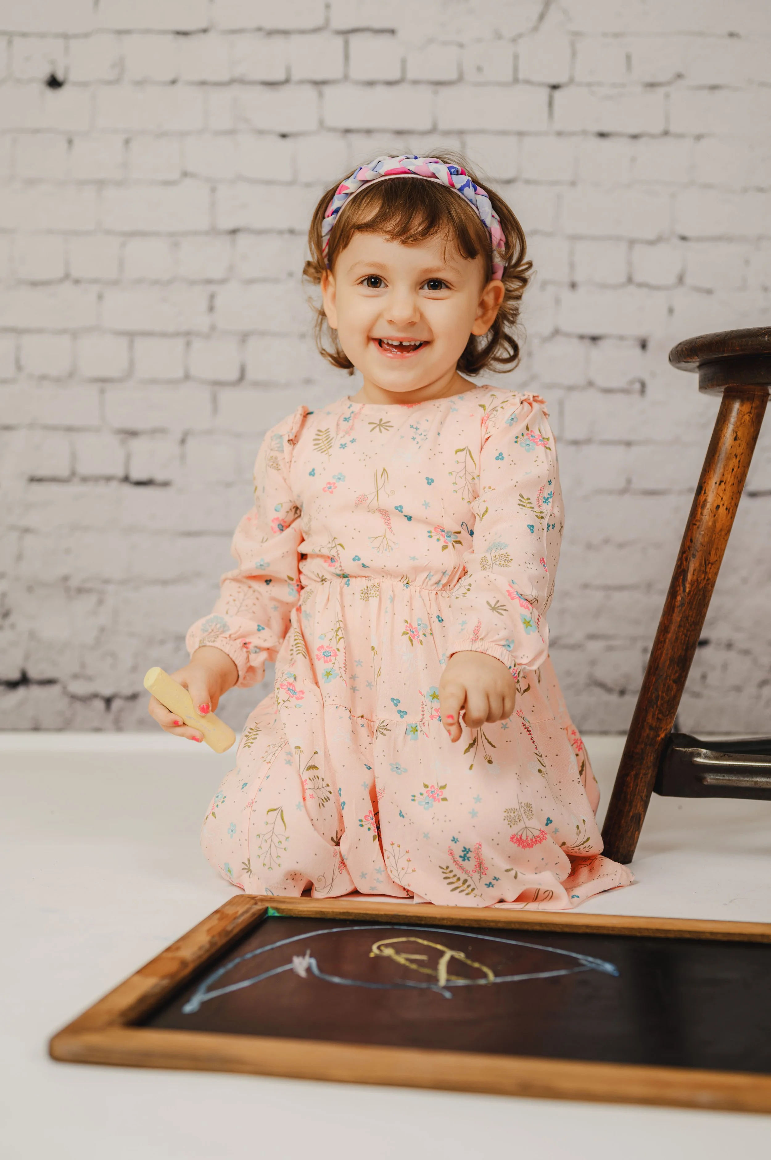 Ein fröhliches Kind sitzt neben einer kleinen Kreidetafel und hält bunte Kreide in der Hand.
Das Kreidetafel-Set schafft eine kreative, ruhige Umgebung, in der Kinder sich frei entfalten können.
Ohne Druck und ohne starre Posen entstehen natürliche P