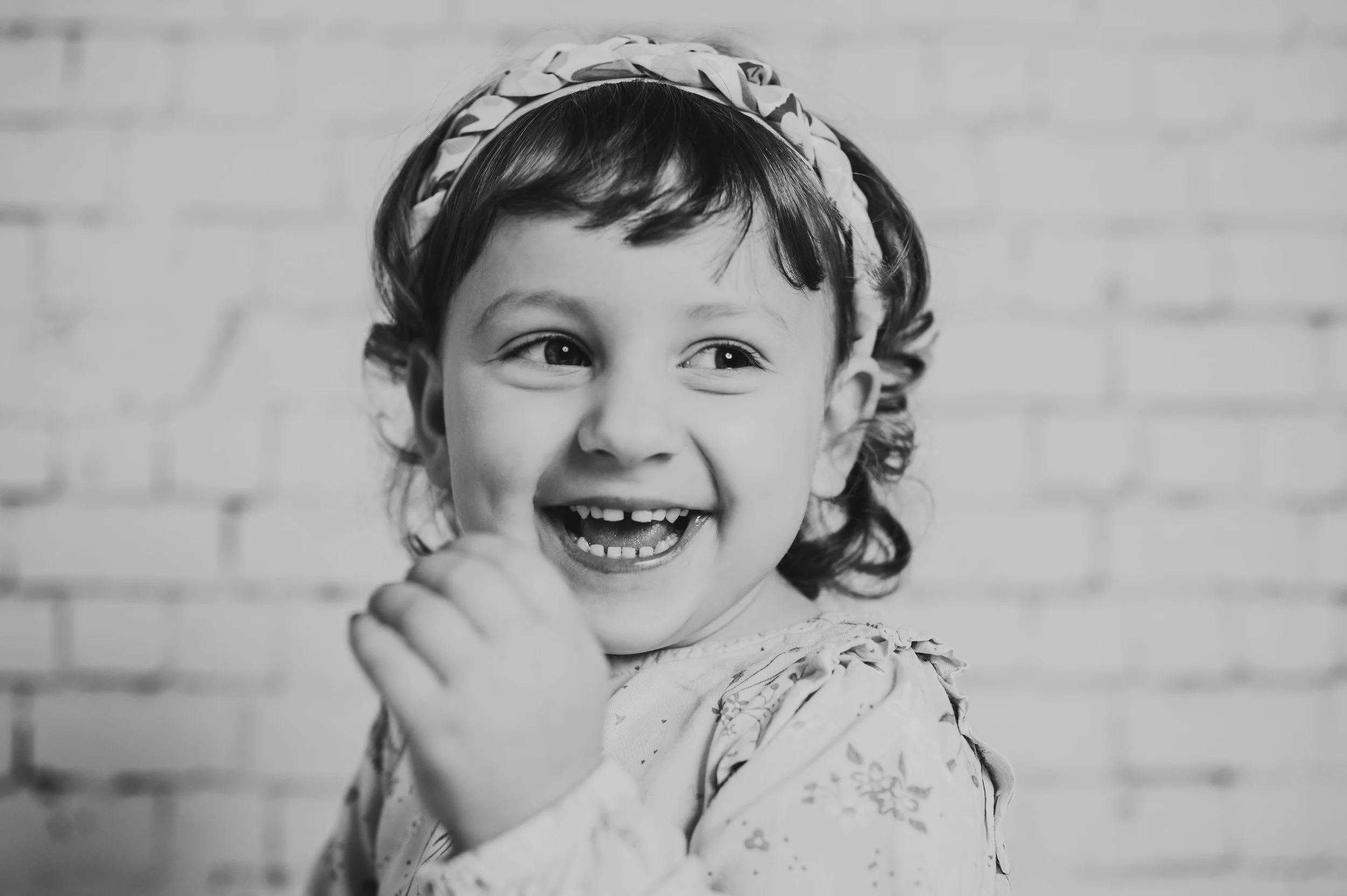 Ausdrucksstarkes Schwarz-Weiß-Porträt im Kreidetafel-Set:
Ein Kind lacht herzhaft und ungestellt vor einer hellen Backsteinwand.
Die reduzierte Schwarz-Weiß-Umsetzung lenkt den Fokus ganz auf Mimik, Emotion und Persönlichkeit.
Zeitlos, ehrlich und oh